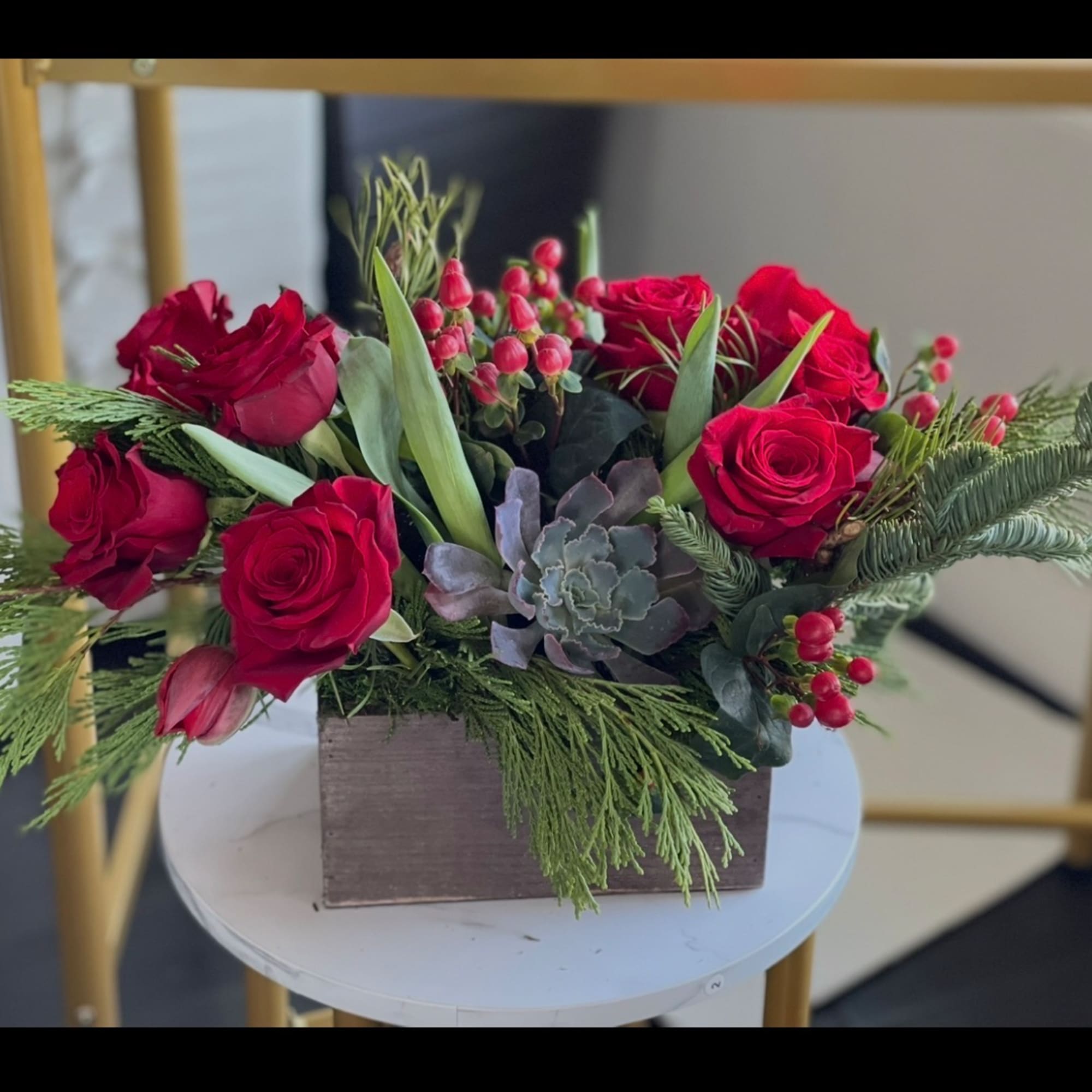 Red roses in a wooden box with succulents and greenery