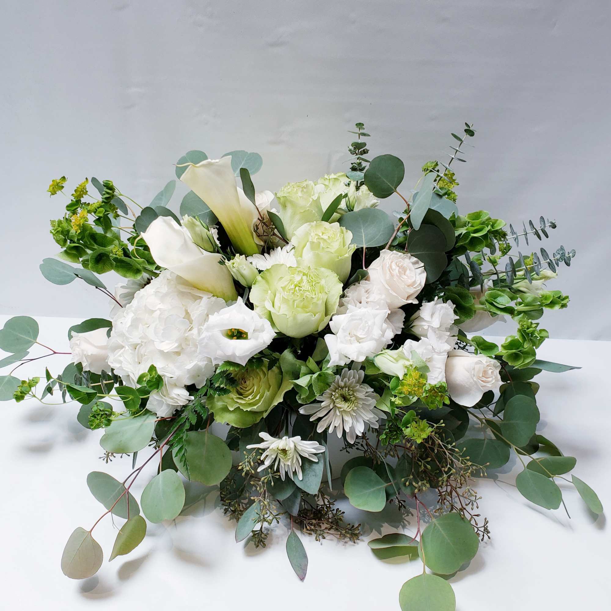 White and pale green floral arrangement with calla lilies and roses