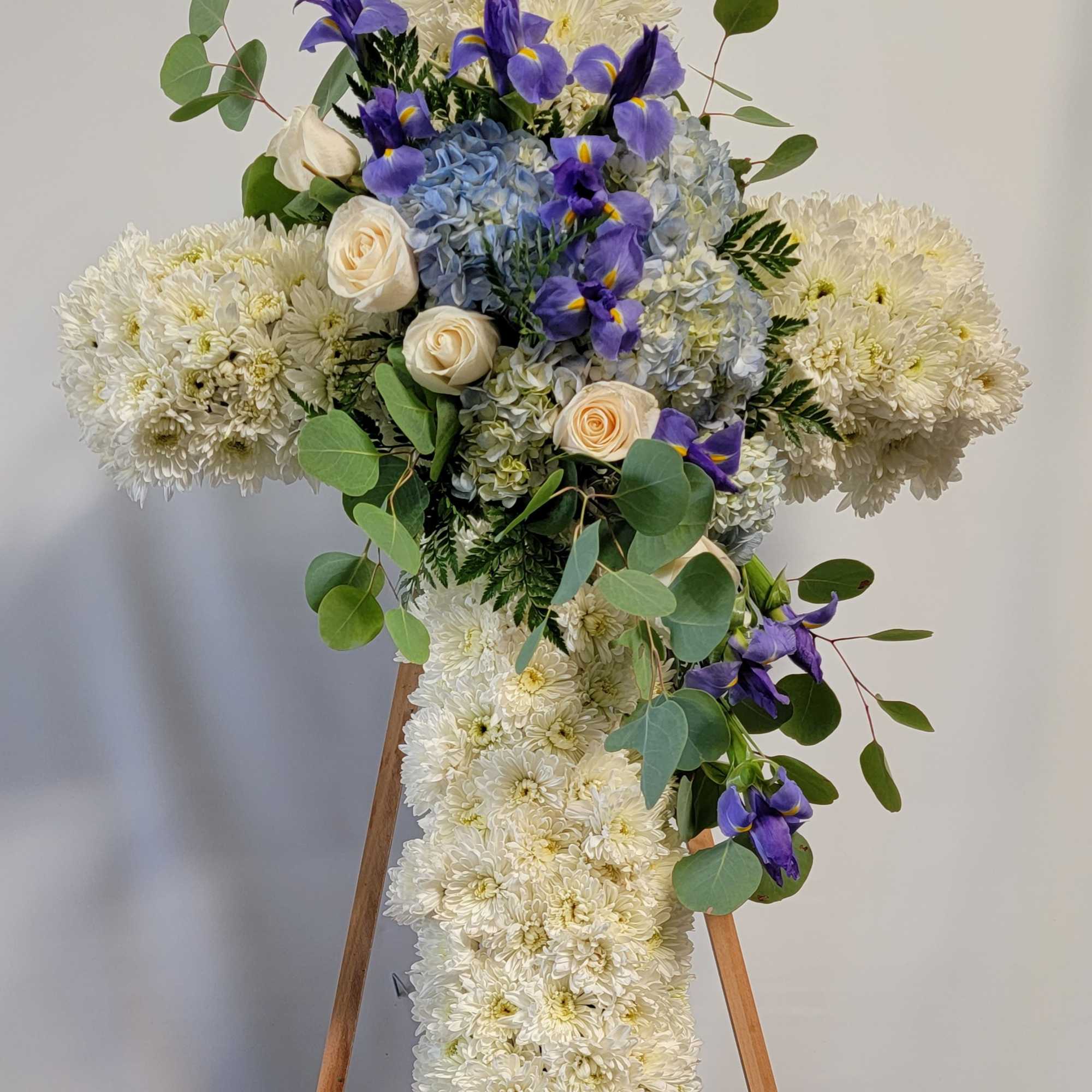 Cross-shaped floral spray with white chrysanthemums, blue hydrangea, and purple irises