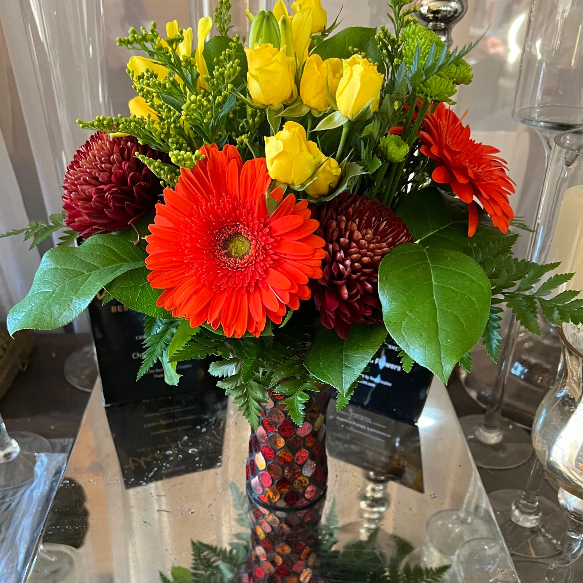 Bright bouquet of yellow roses and red gerbera daisies in a mosaic vase