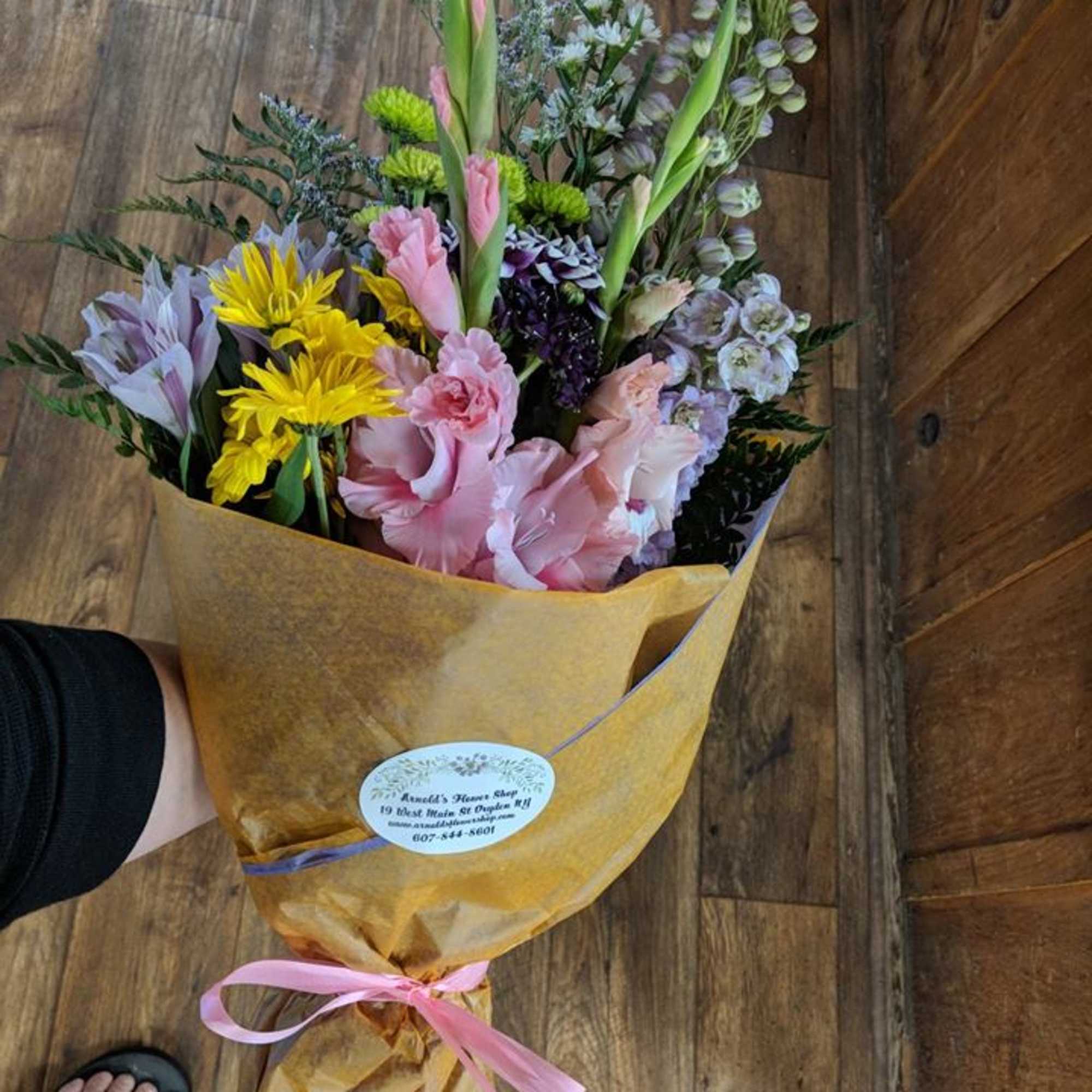 Mixed bouquet of pink, yellow, and lavender flowers wrapped in gold paper