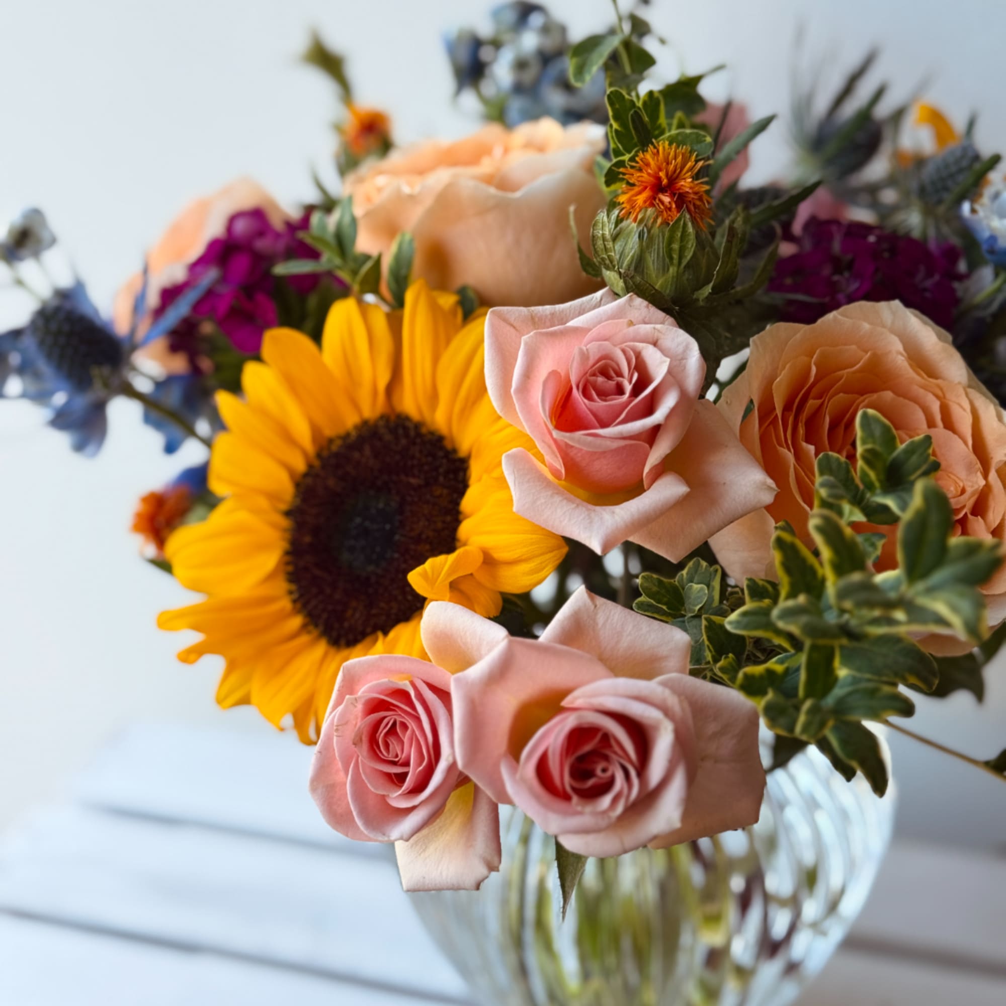 Bouquet of pink roses and a sunflower in a glass vase