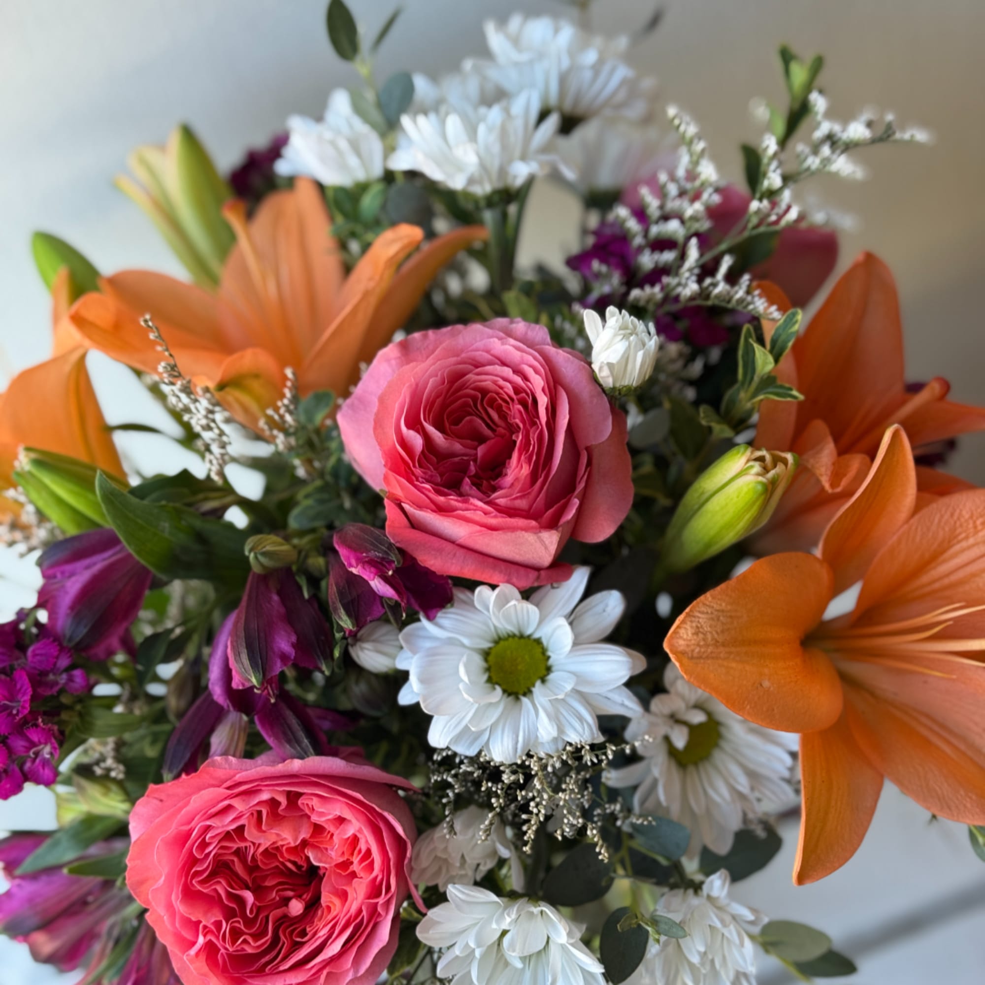 Bouquet of pink roses, orange lilies, and white daisies