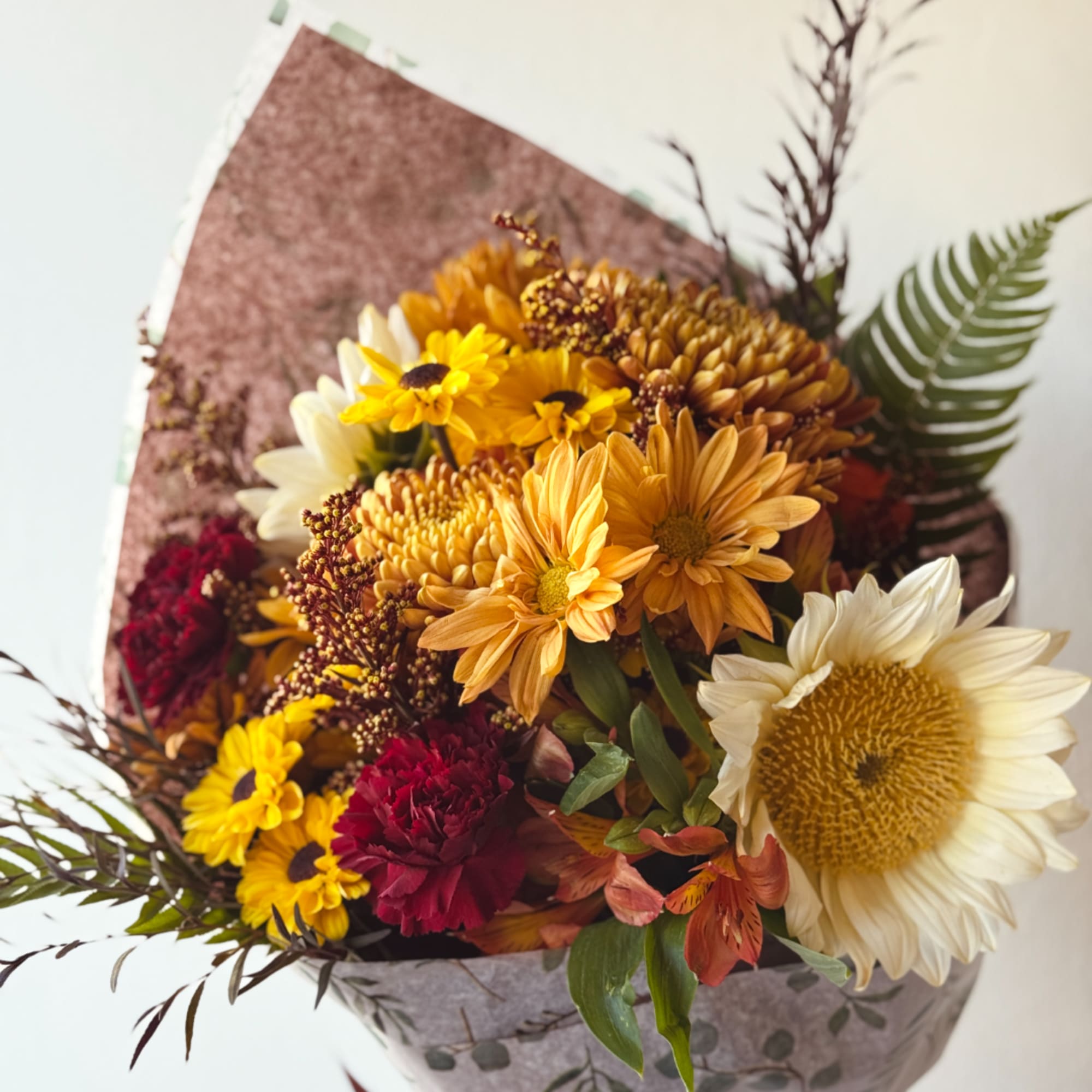 Bouquet of yellow, white, and burgundy flowers wrapped in paper