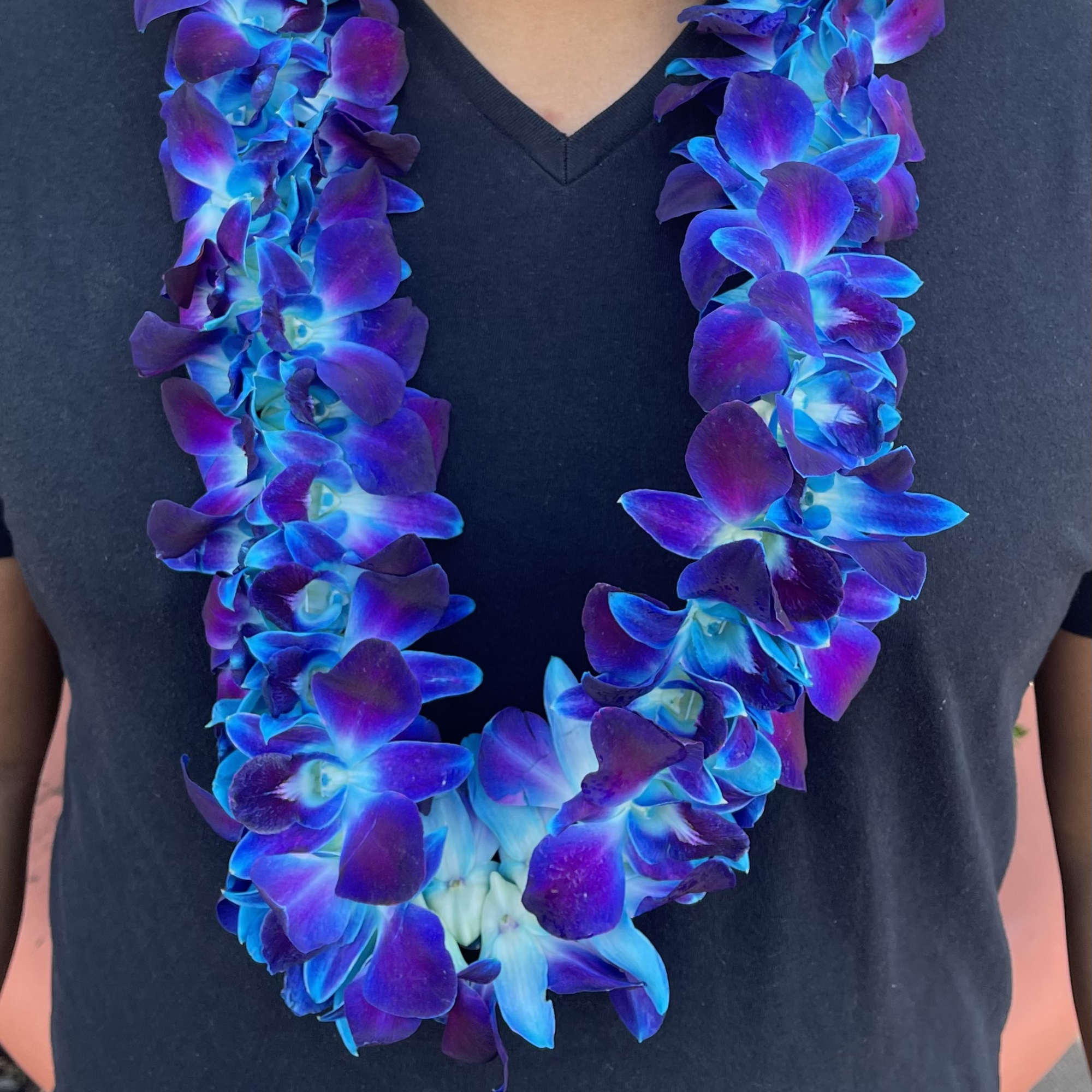 Blue and purple orchid lei worn around a black shirt