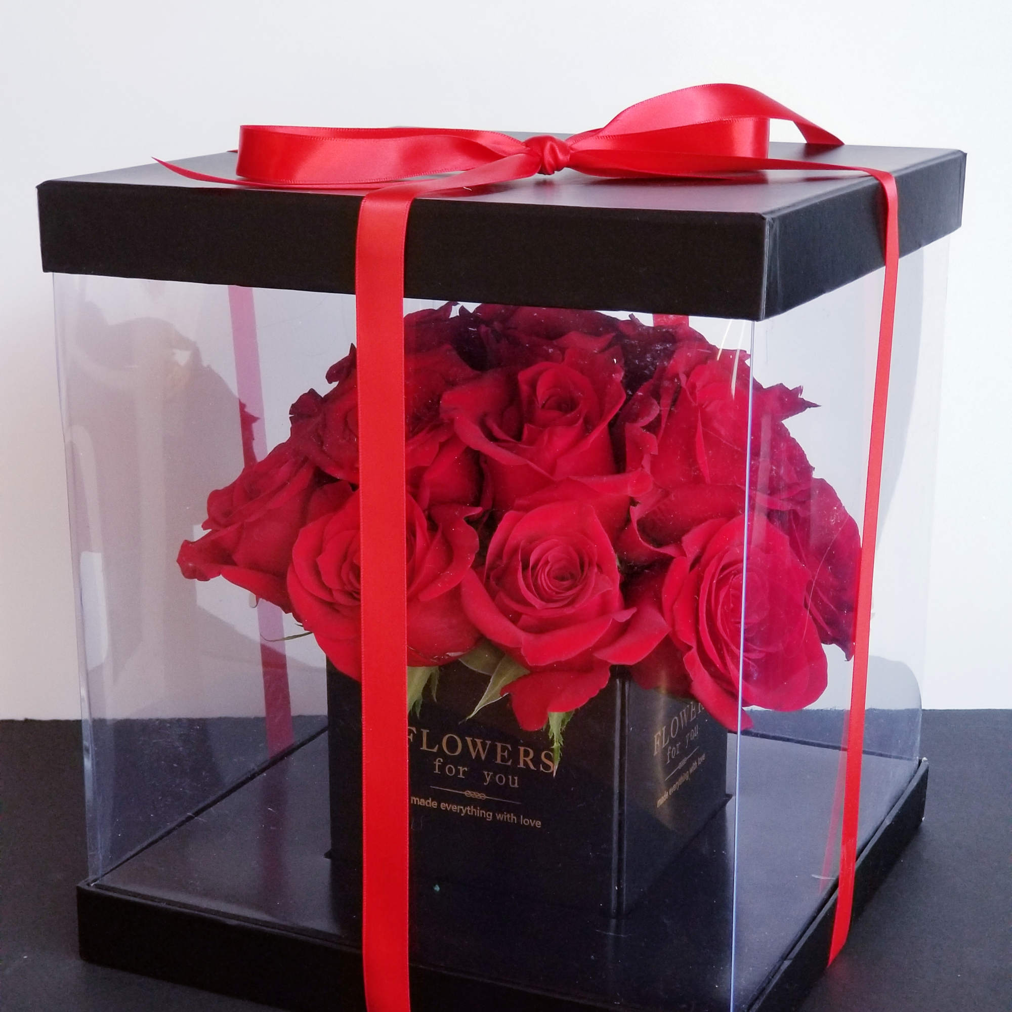 Red roses in a clear gift box tied with a red ribbon