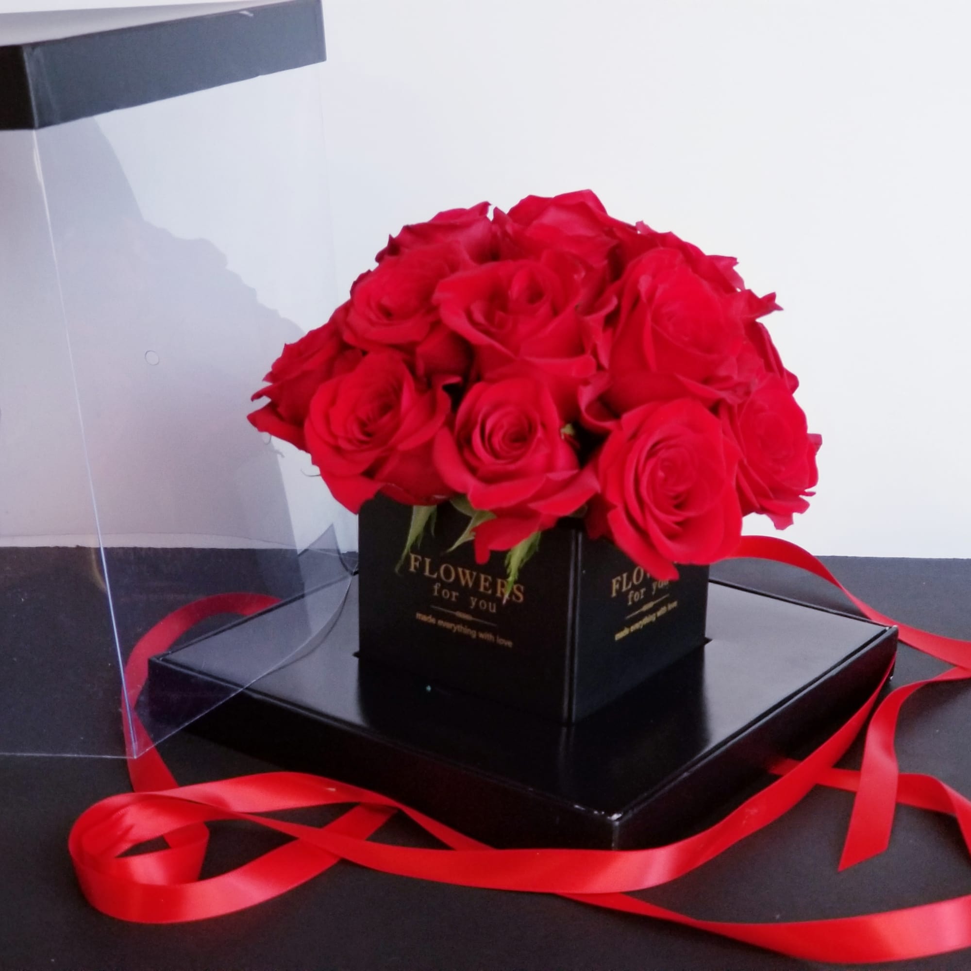 Red roses arranged in a black square box with a red ribbon
