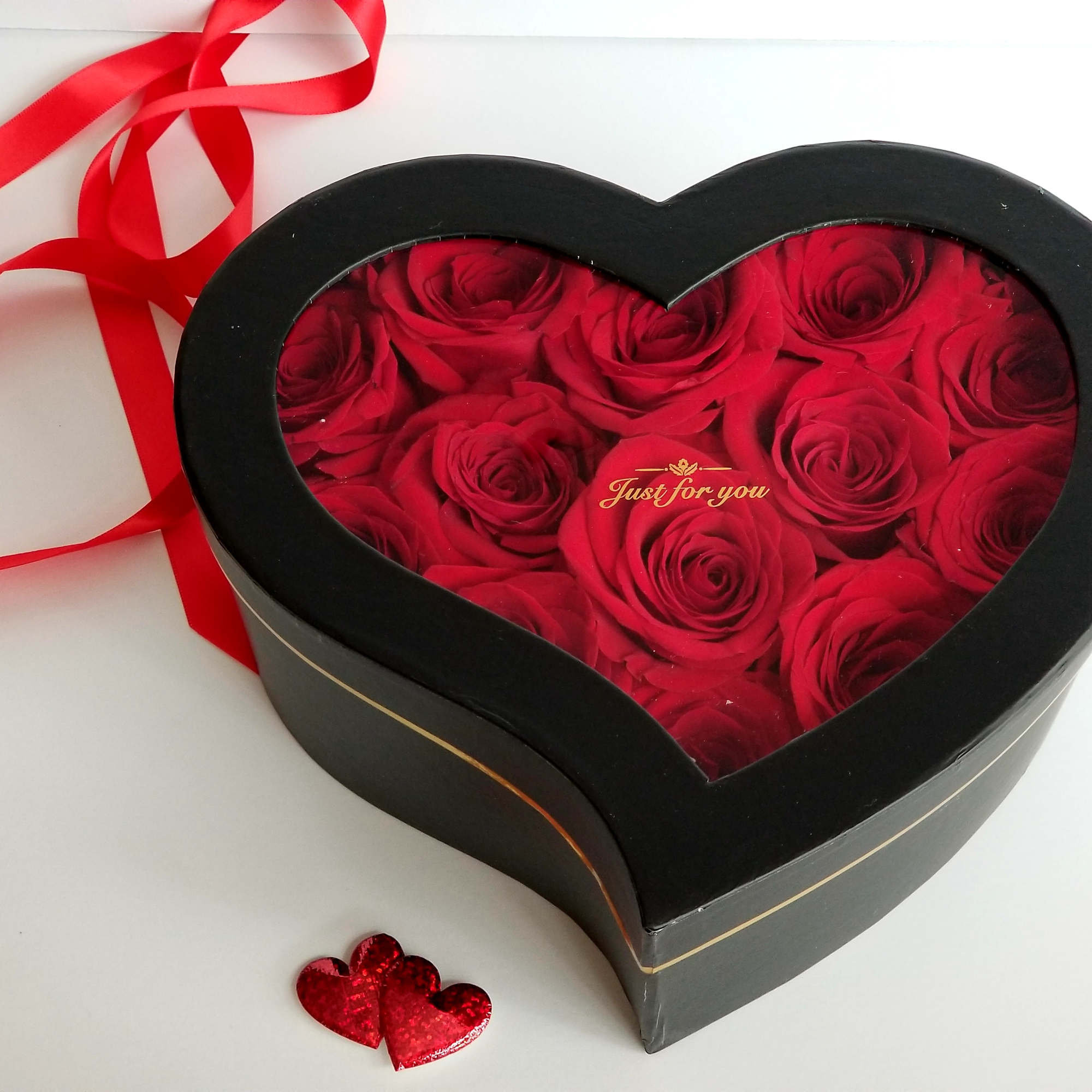 Heart-shaped box of red roses with a red ribbon and heart decoration