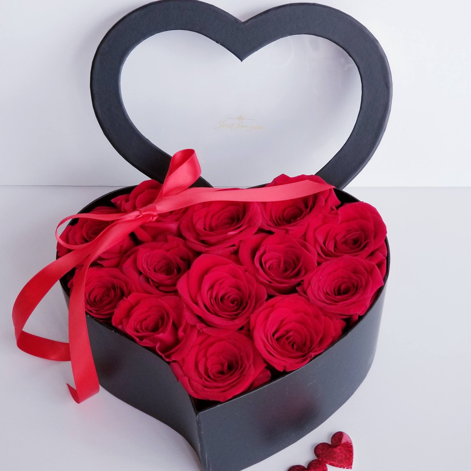 Heart-shaped box filled with red roses and a red ribbon