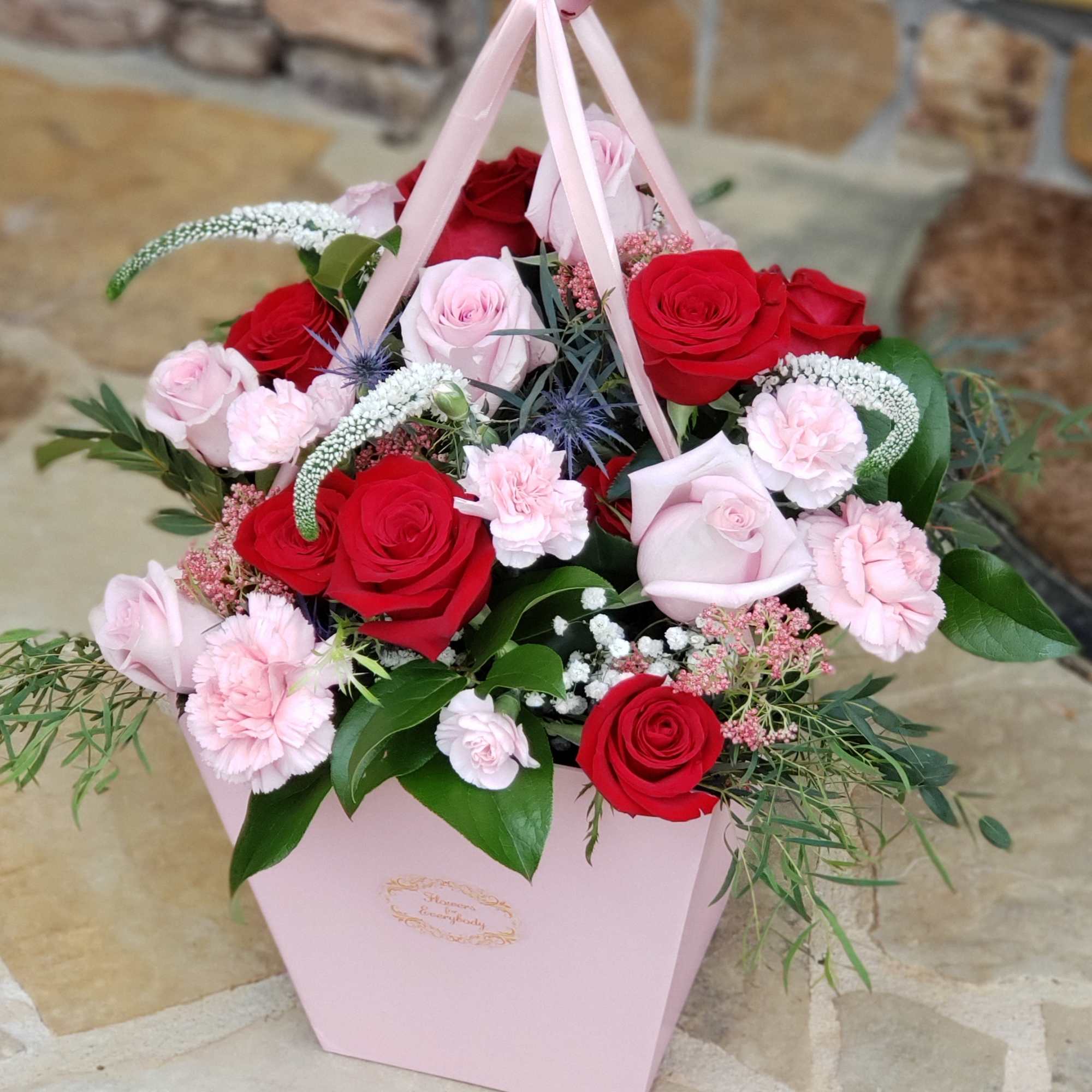 Pink gift box filled with red and pale pink roses and carnations