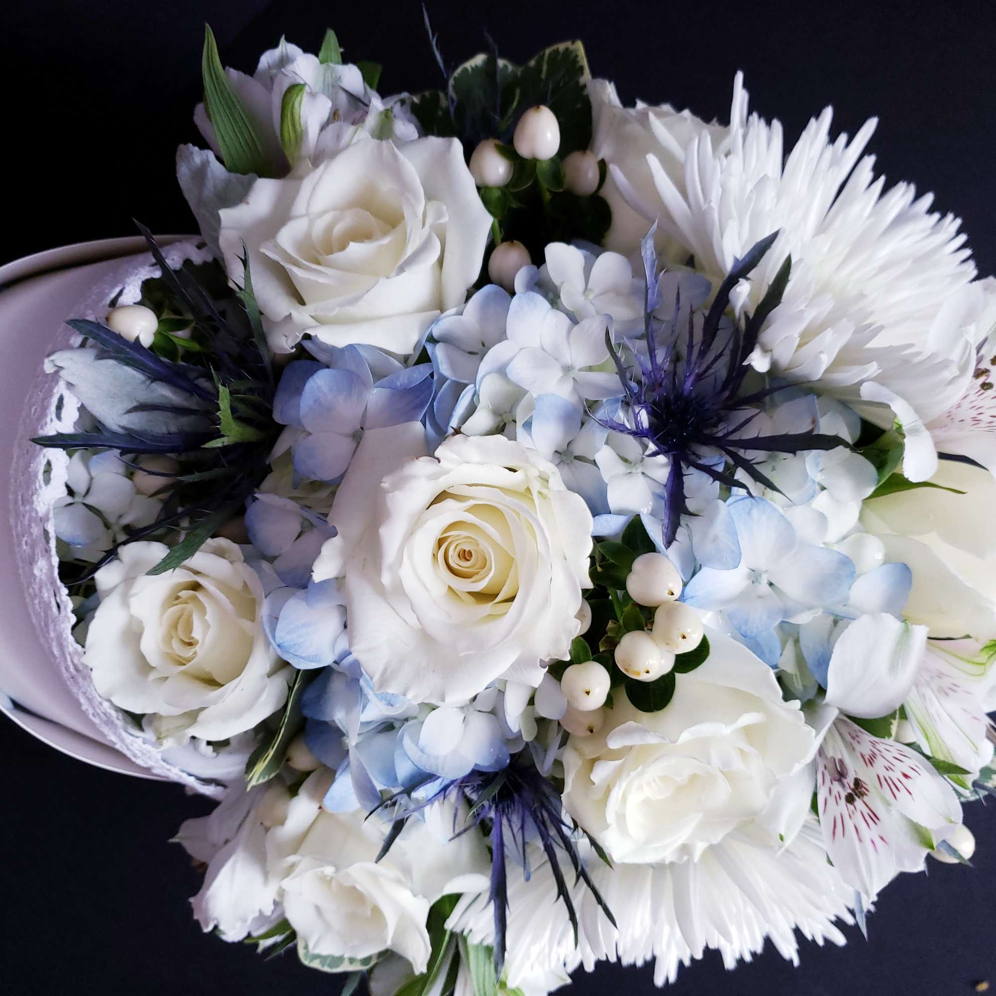 White roses and pale blue hydrangeas in a lavender hatbox bouquet