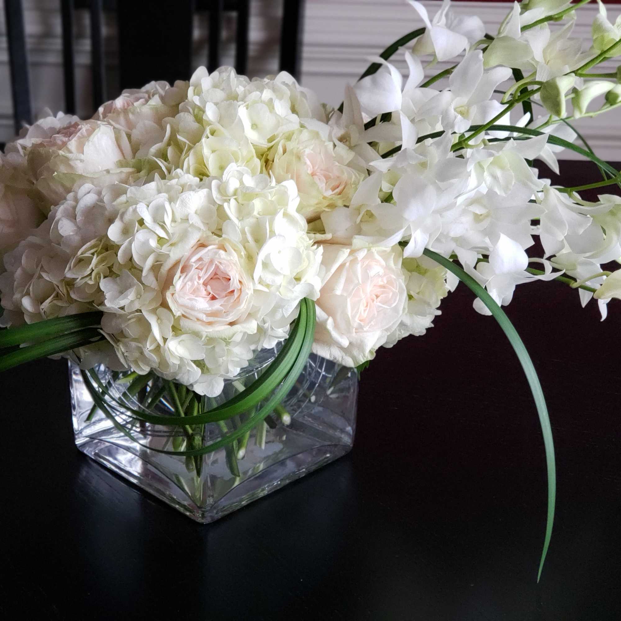 White floral arrangement in a clear square glass vase