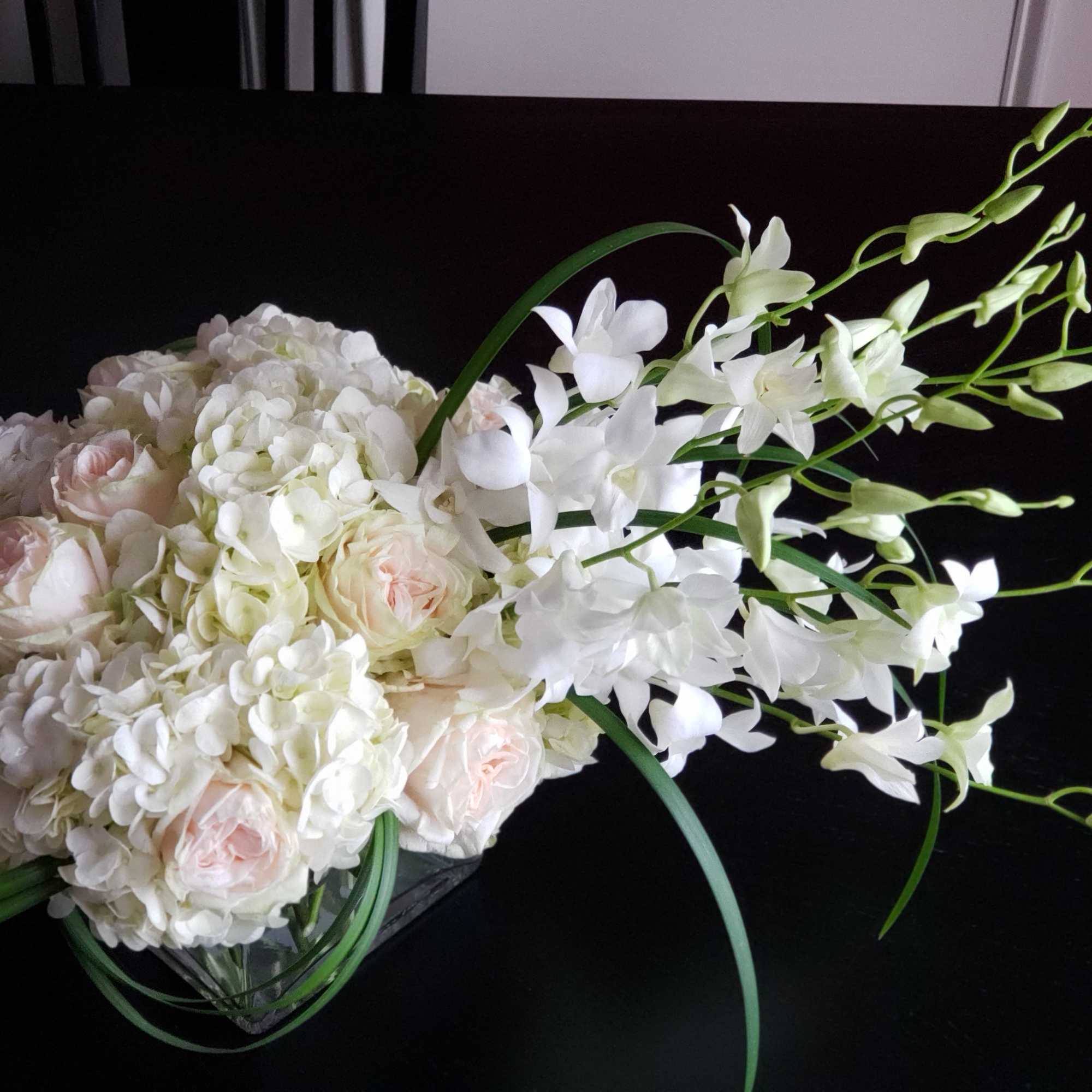 White and blush bouquet with orchids and roses in a glass vase