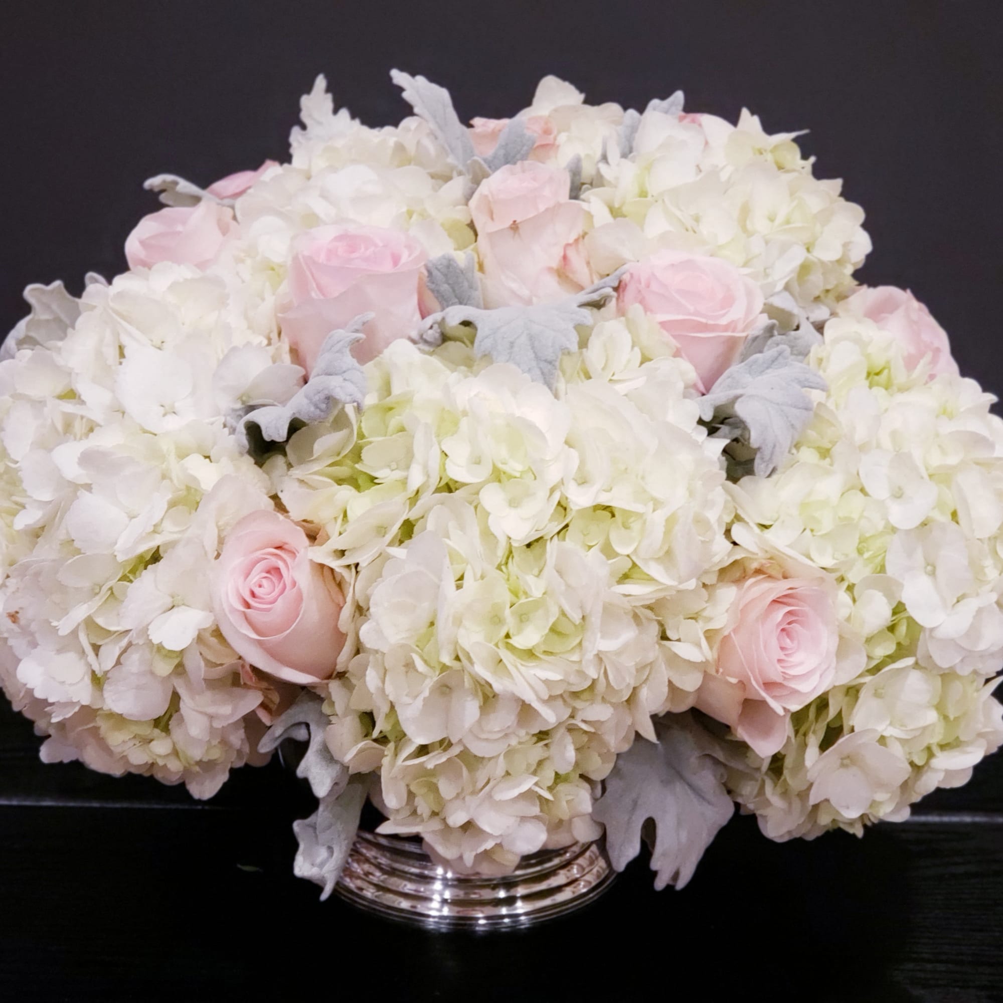 White hydrangeas and pale pink roses in a silver vase
