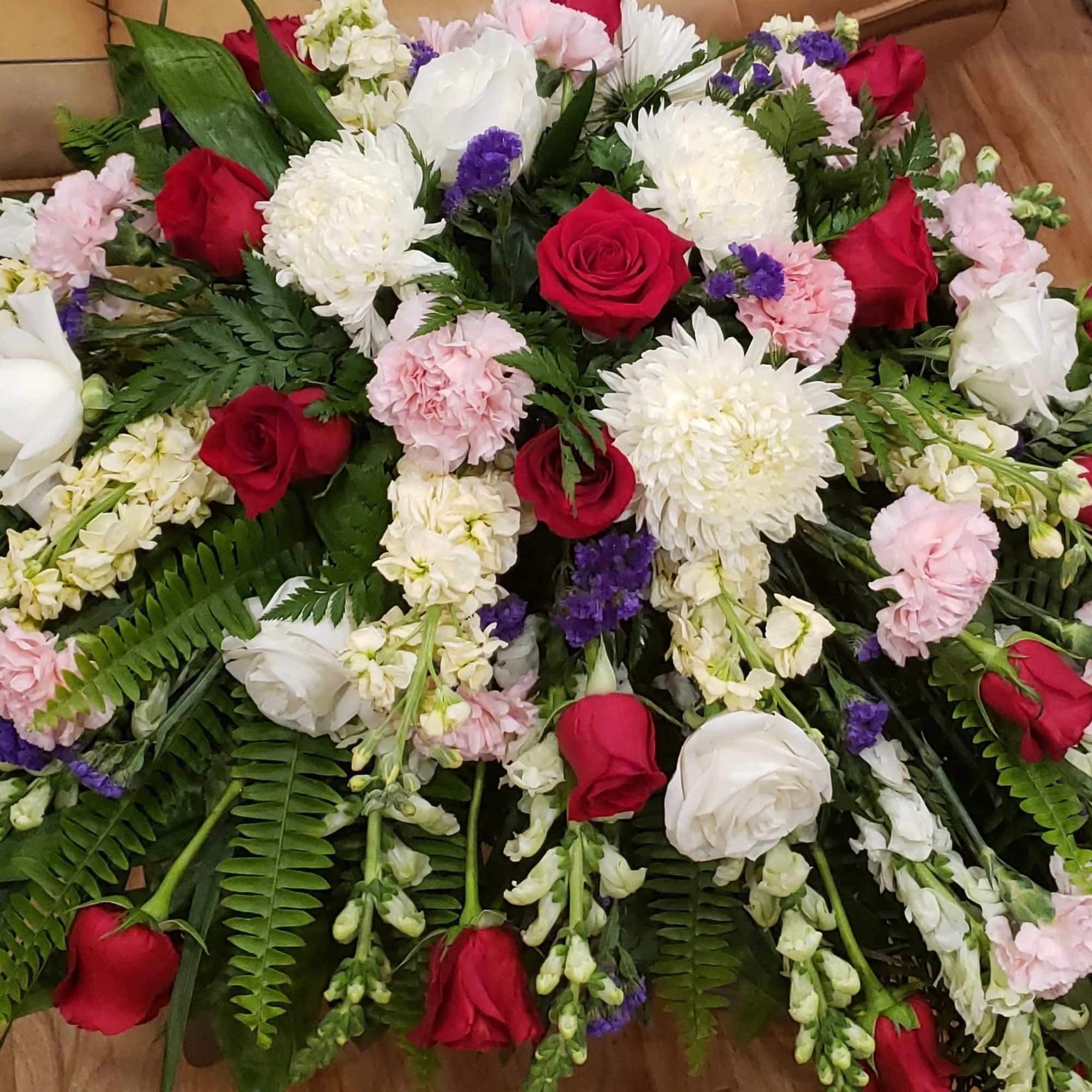 Casket spray of red and white roses with pink carnations and white chrysanthemums