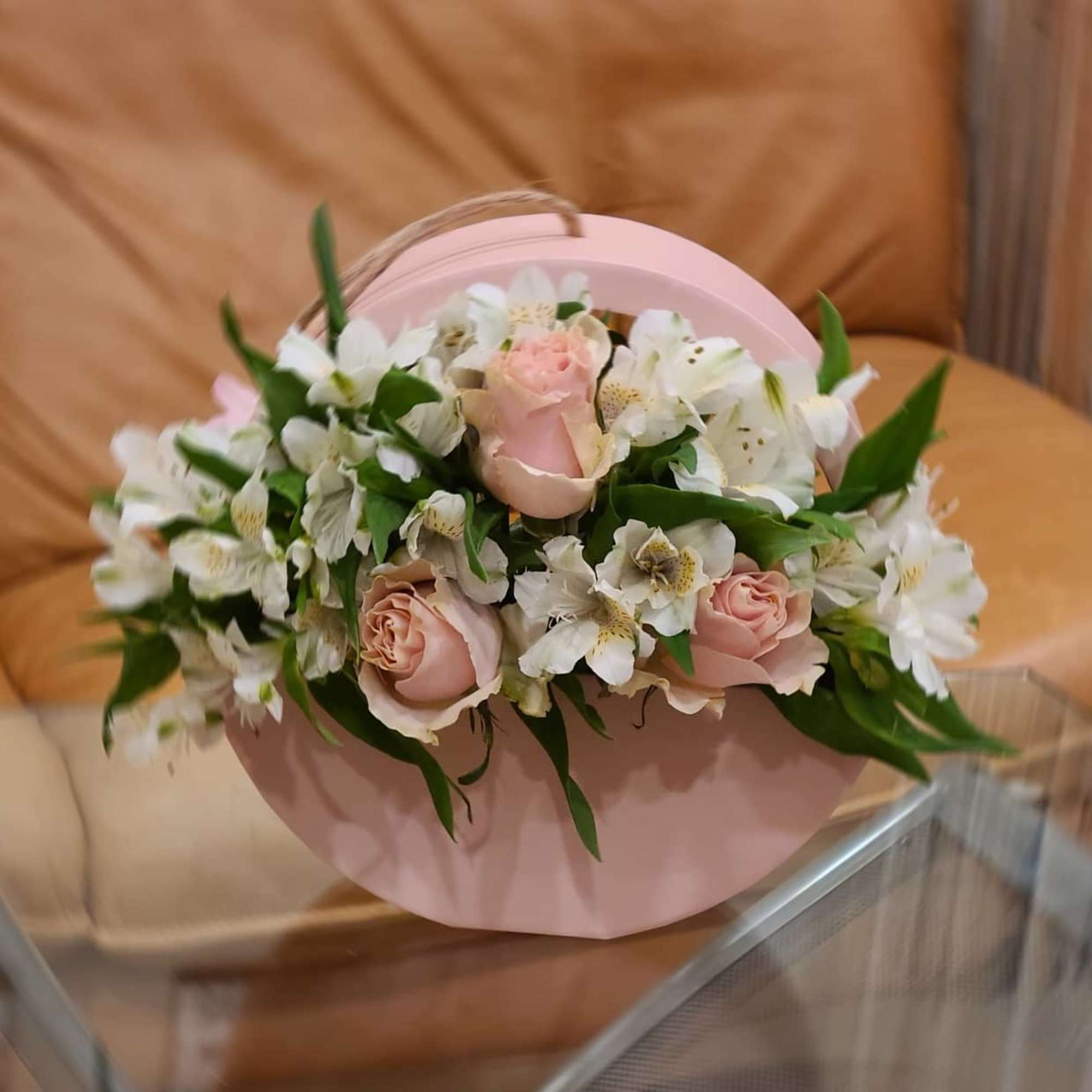 Pink roses and white flowers arranged in a round pink box