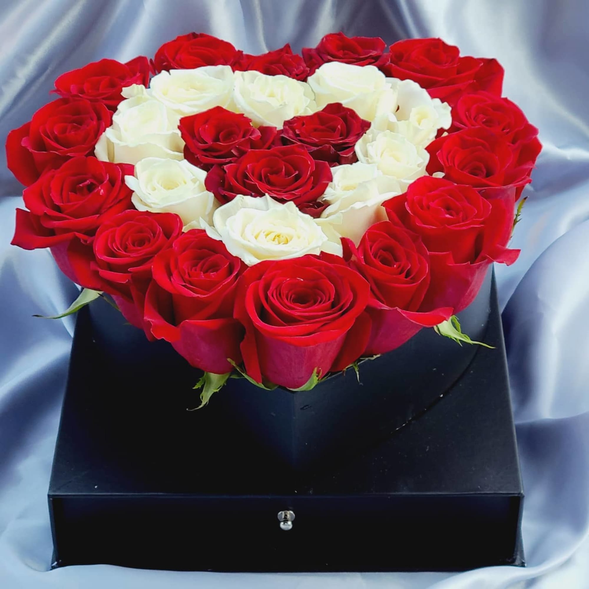 Red and white roses arranged in a black presentation box