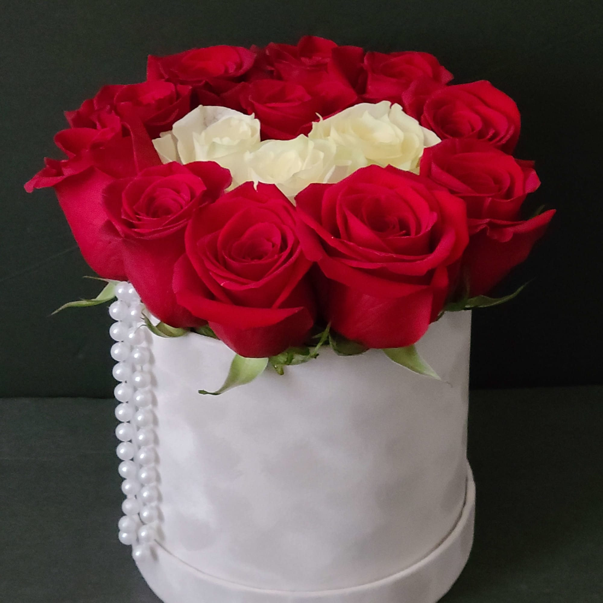 Red and white roses arranged in a white round box with pearl trim