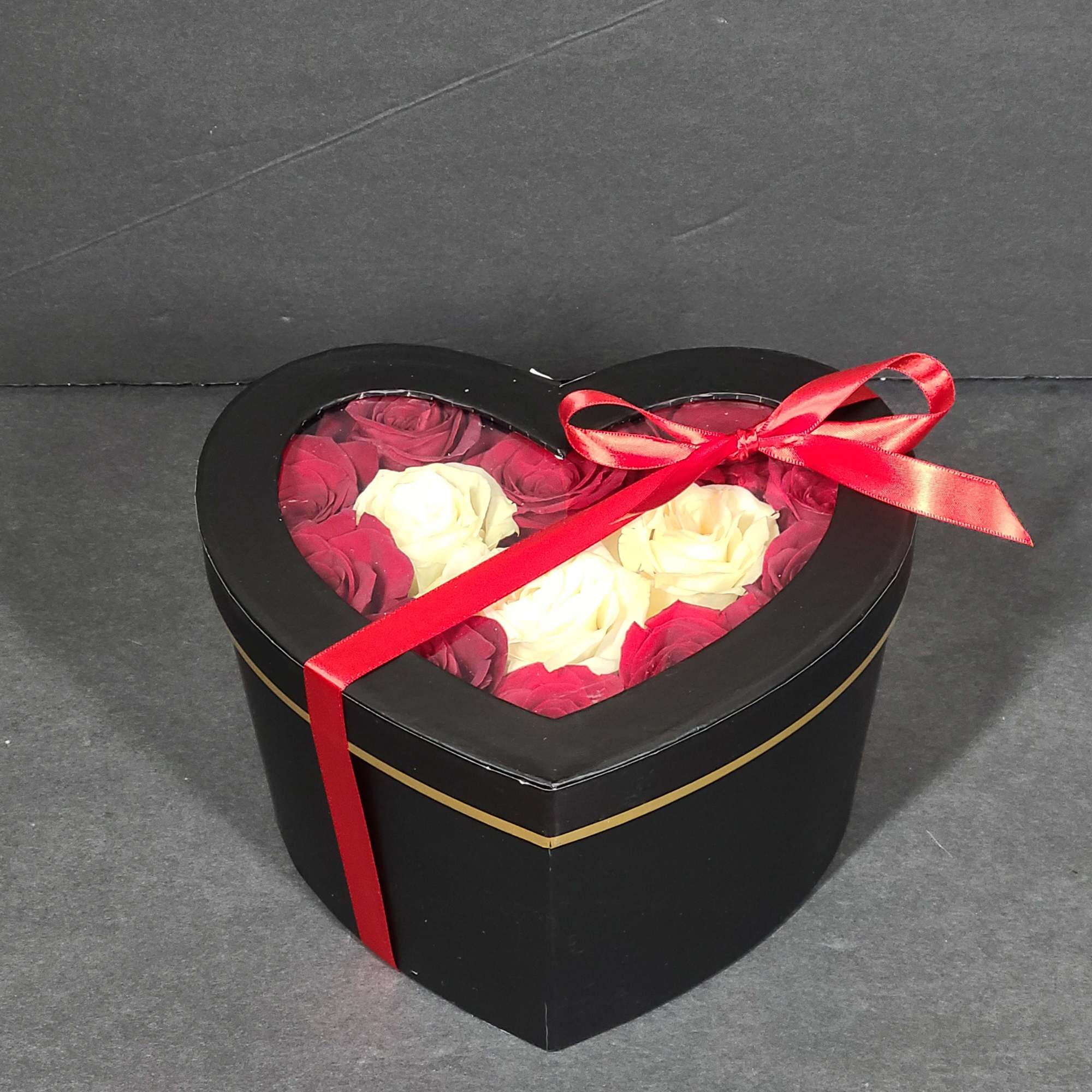 Heart-shaped box of red and white roses tied with a red ribbon