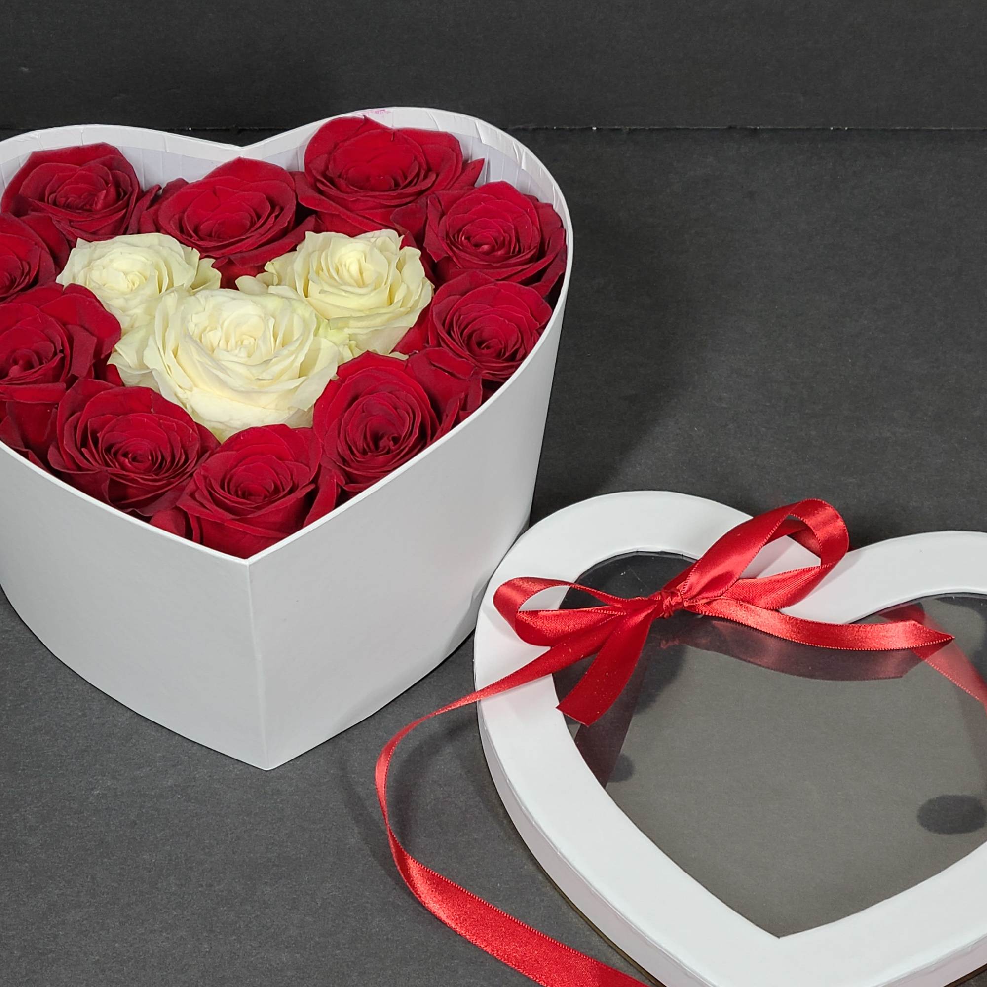 Heart-shaped box of red and white roses with a matching lid and ribbon