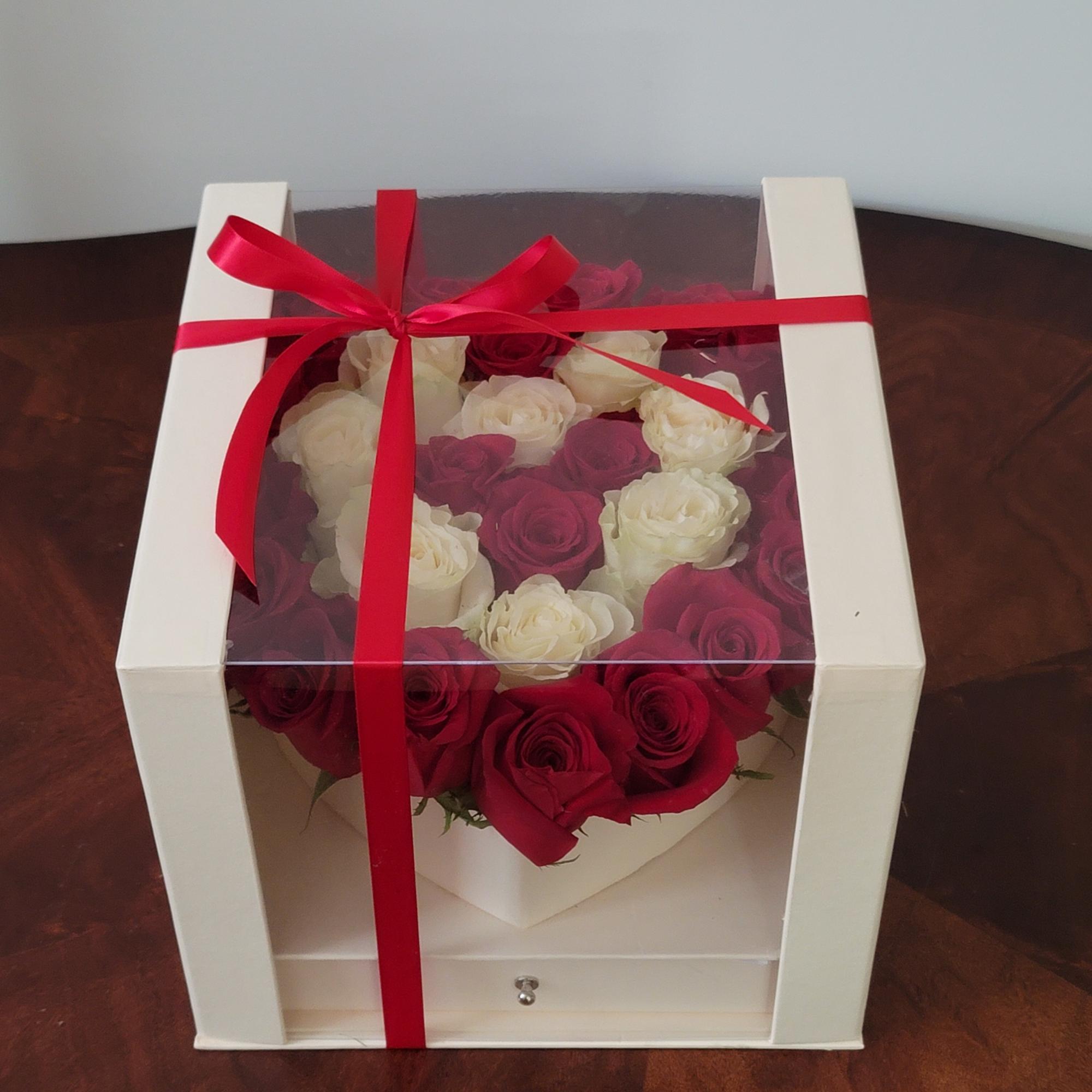 Boxed arrangement of red and white roses tied with a red ribbon