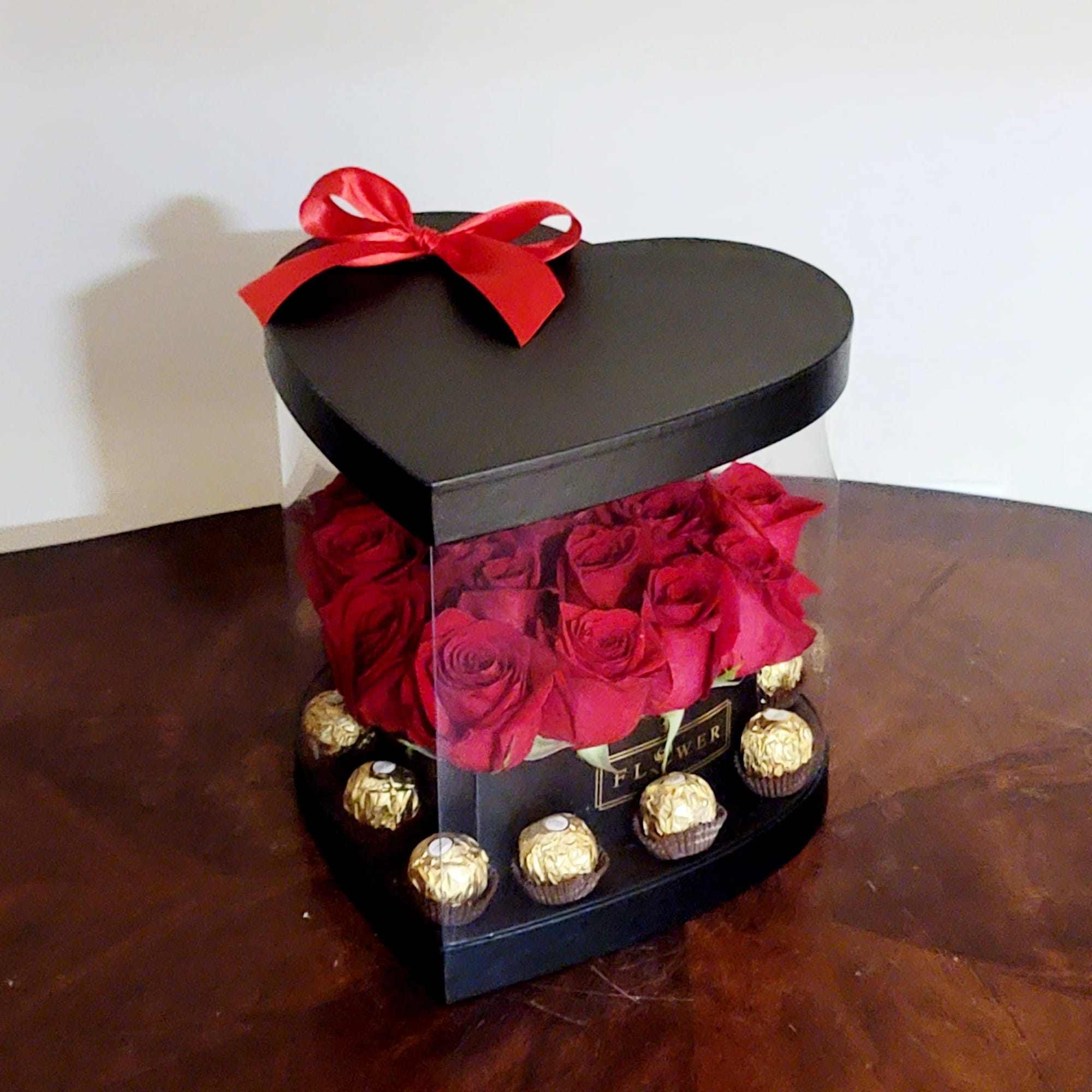 Heart-shaped box of red roses with gold-wrapped chocolates and a red bow