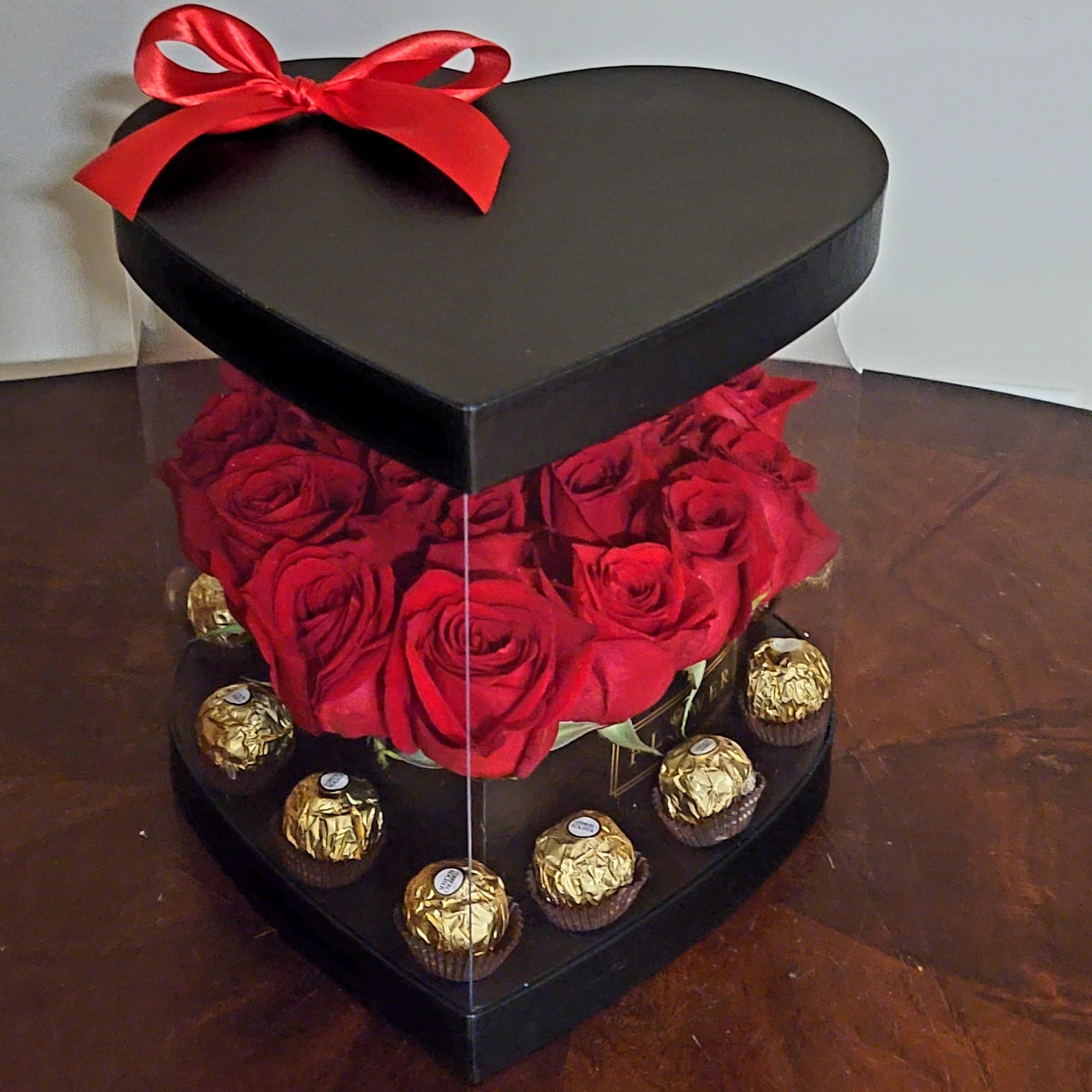 Heart-shaped box with red roses and chocolates, topped with a red bow