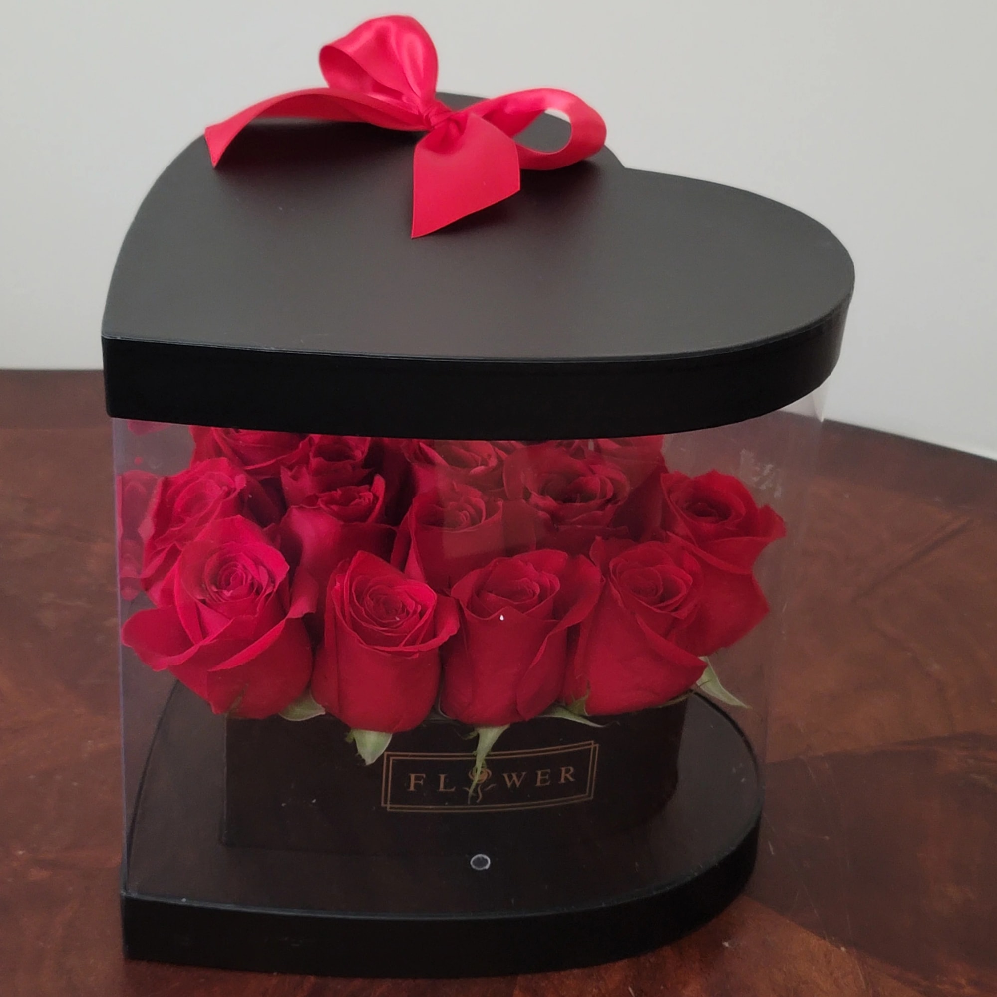 Red roses in a black heart-shaped gift box with a pink ribbon