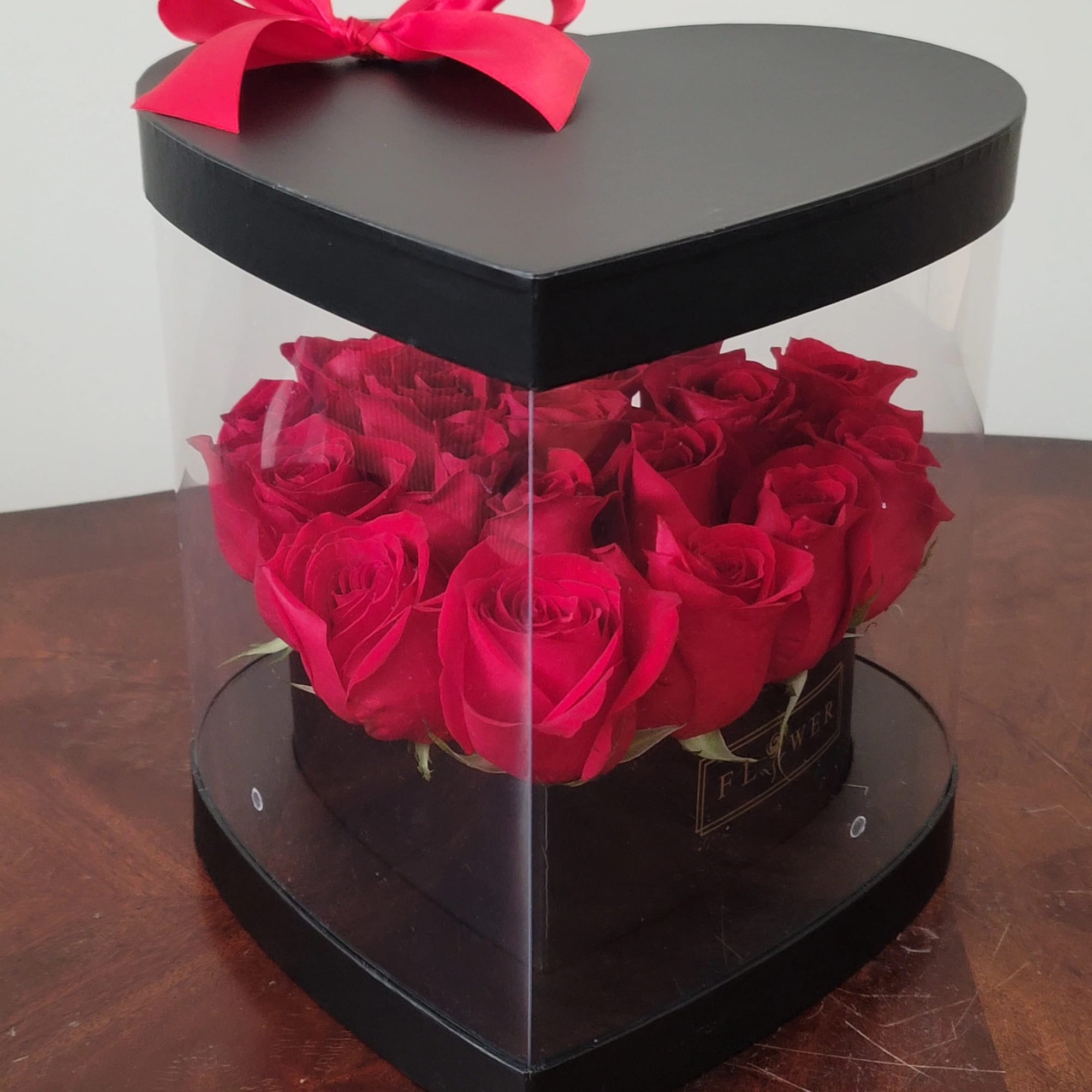 Heart-shaped box of red roses with a pink ribbon bow