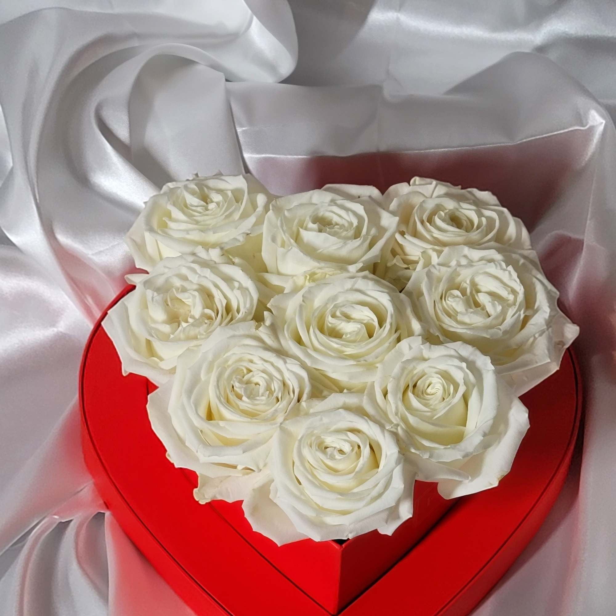 White roses arranged in a red heart-shaped box