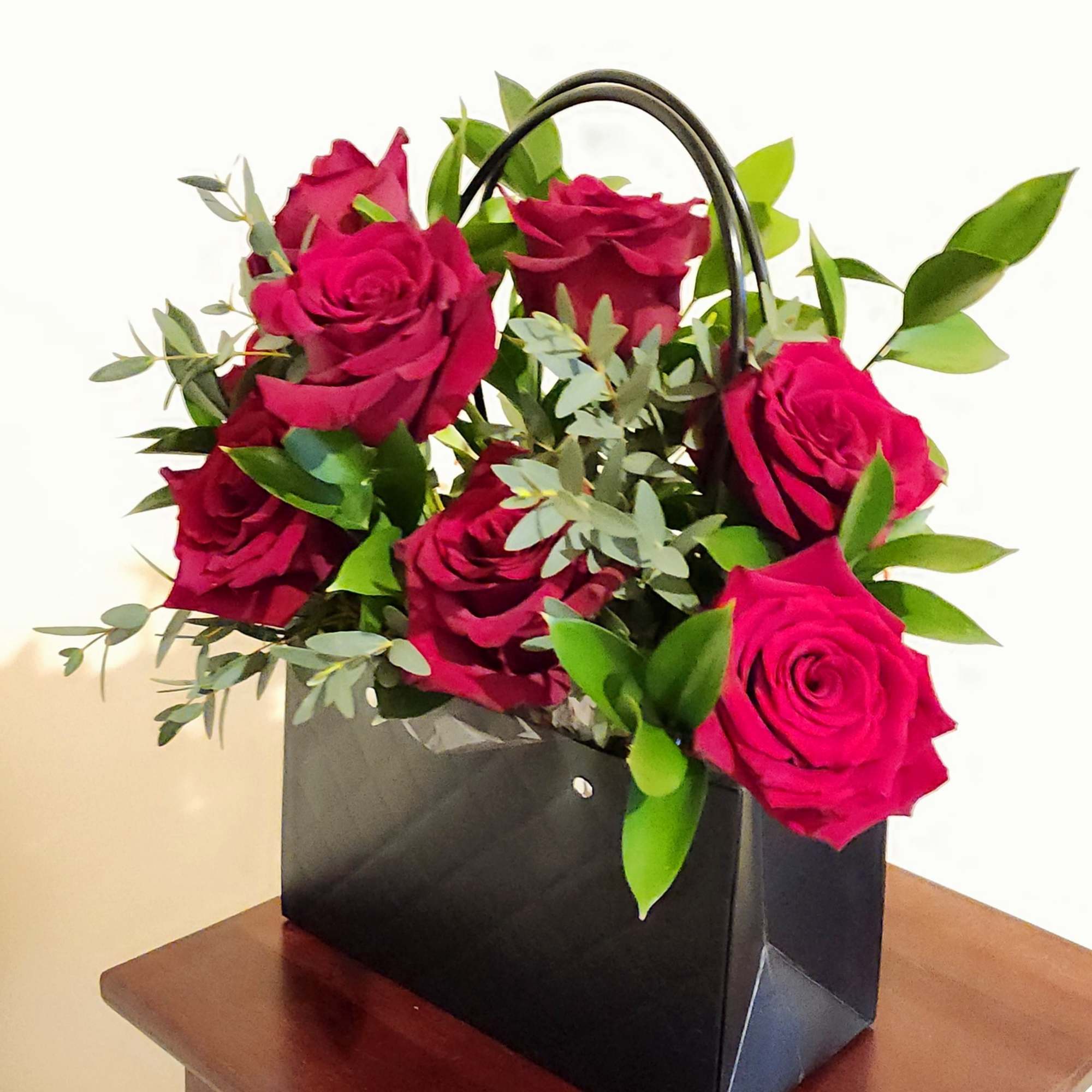 Pink roses arranged in a black handled gift bag