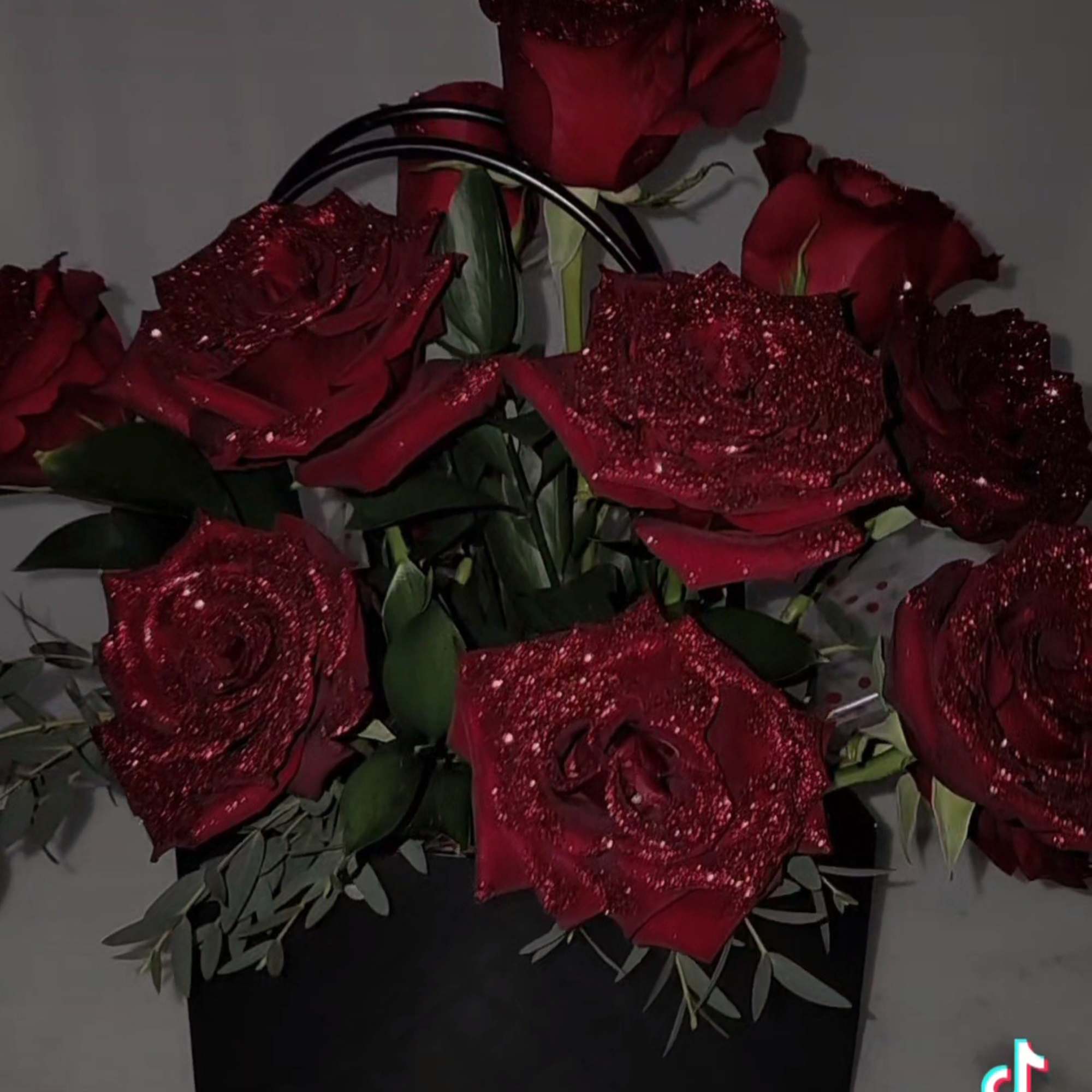 Bouquet of red roses with glitter accents in a black gift bag
