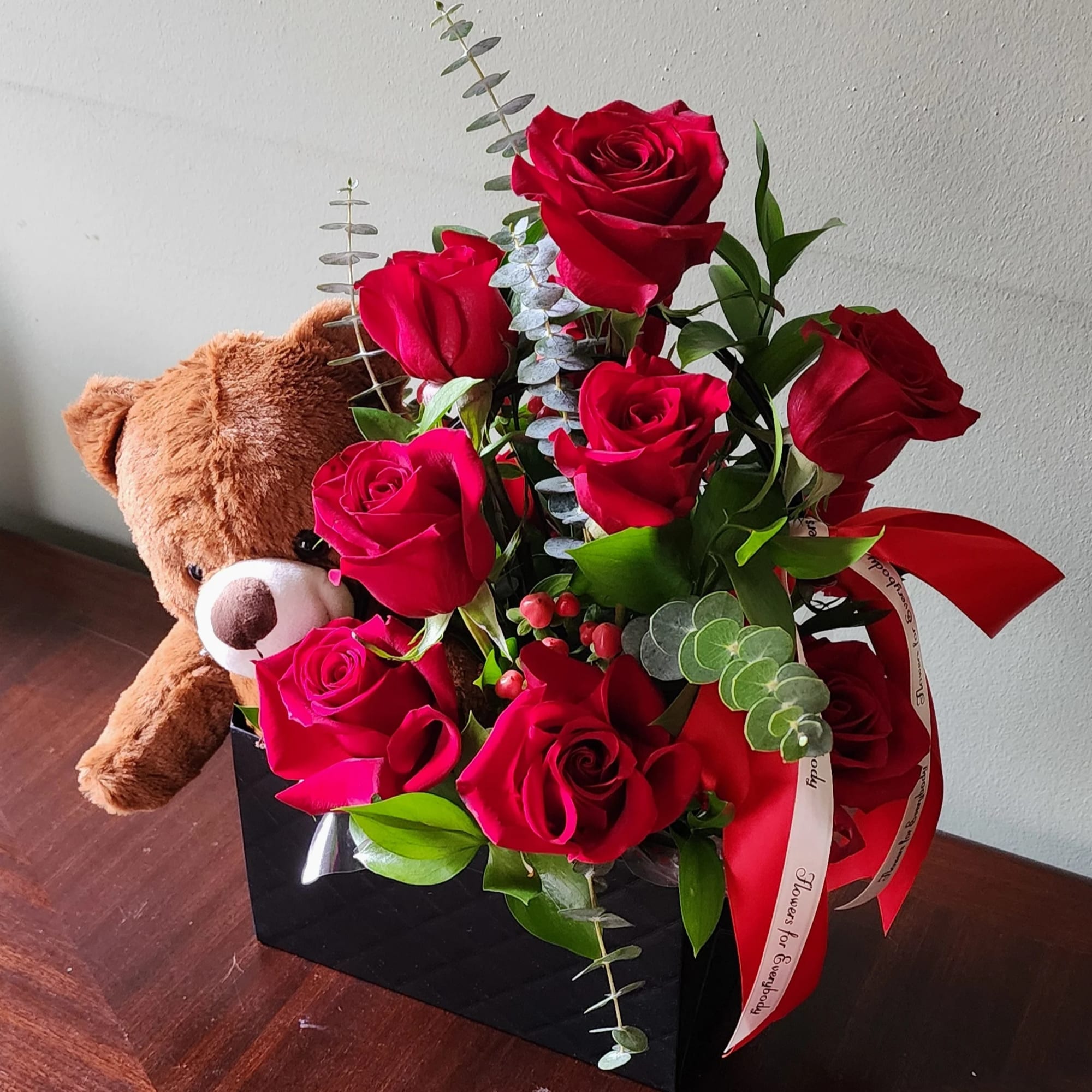 Red roses in a black gift box with a teddy bear