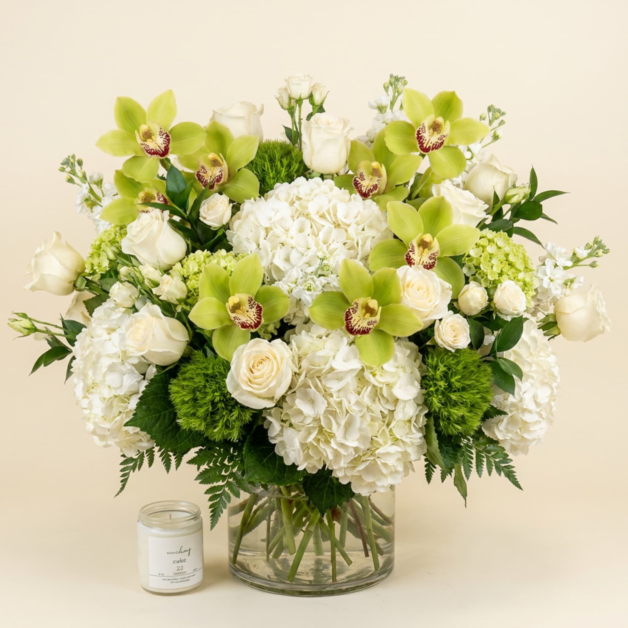 White hydrangeas and roses with green orchids in a glass vase