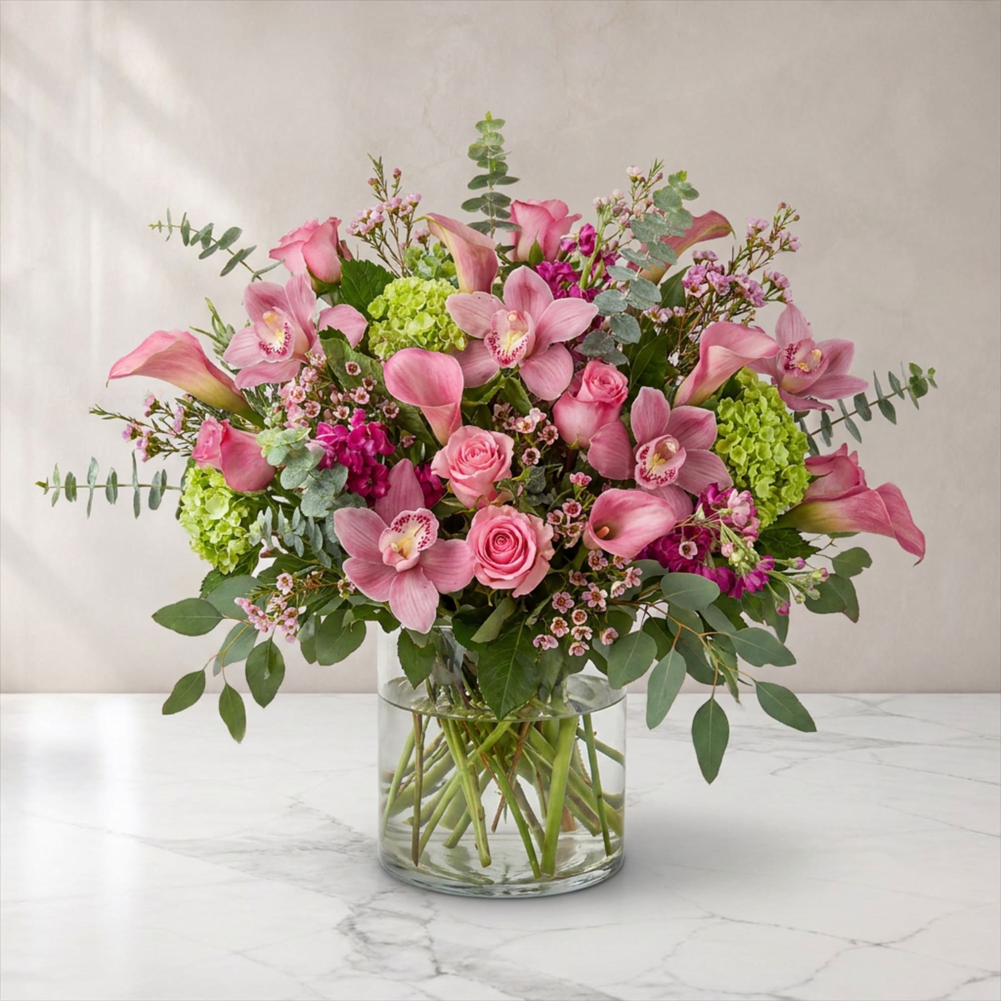 Pink flowers in a clear glass vase with green accents