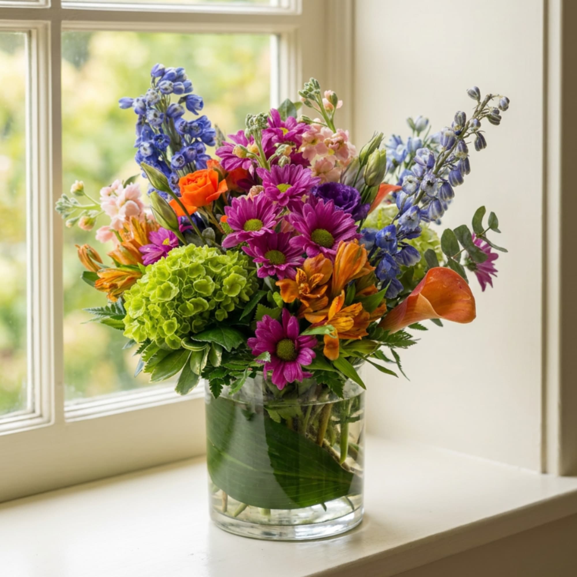 Colorful mixed bouquet in a clear glass vase on a windowsill