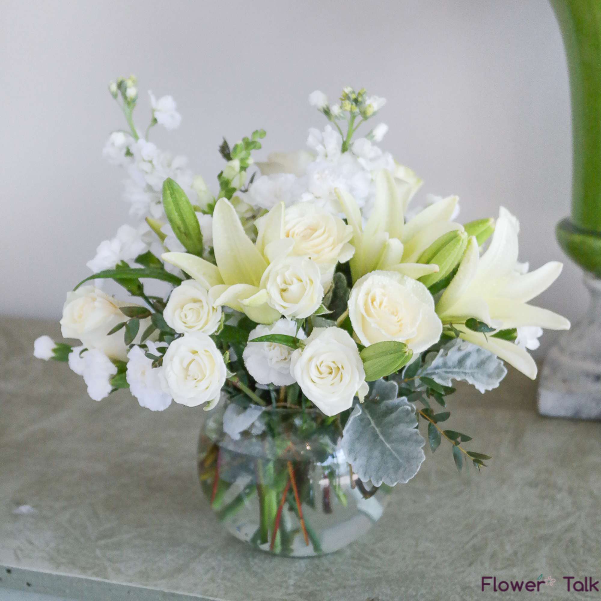 White roses and lilies arranged in a clear glass vase