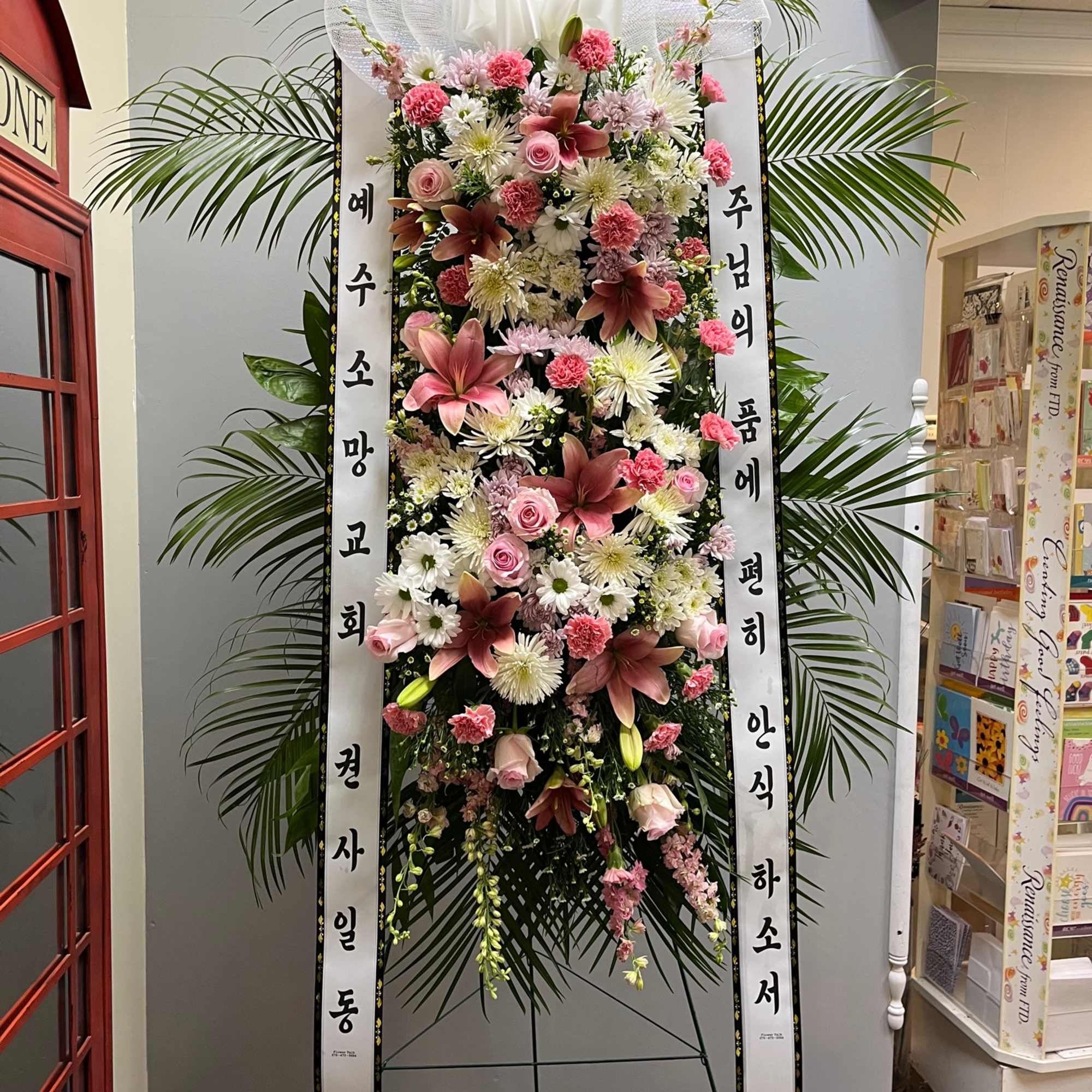 Tall standing floral wreath with pink and white flowers and Korean condolence ribbons