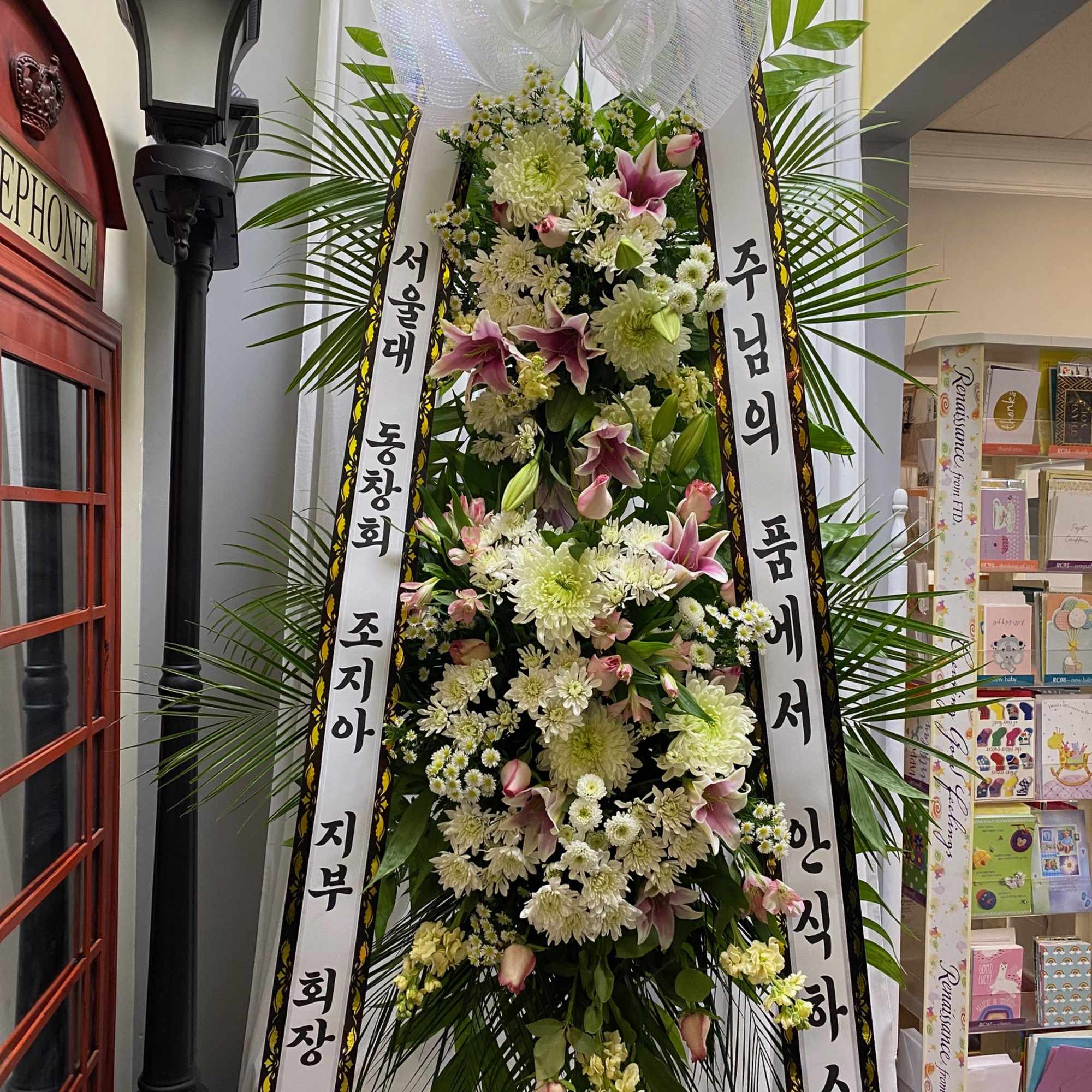Tall standing floral wreath with white and pink flowers and Korean condolence ribbons