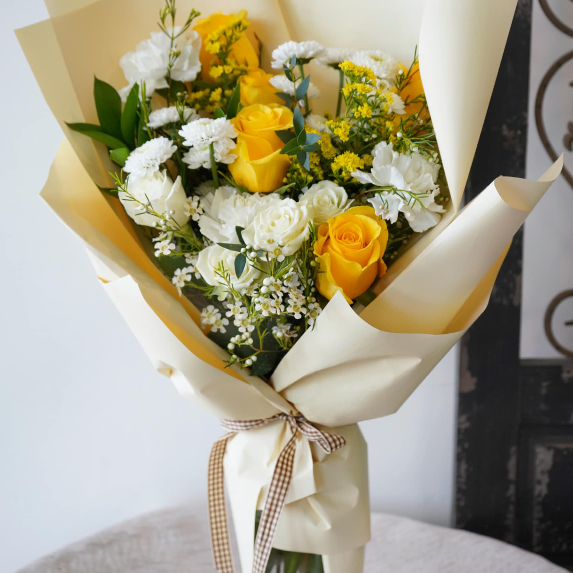 A radiant blend of sunny yellow roses, delicate white spray roses, and