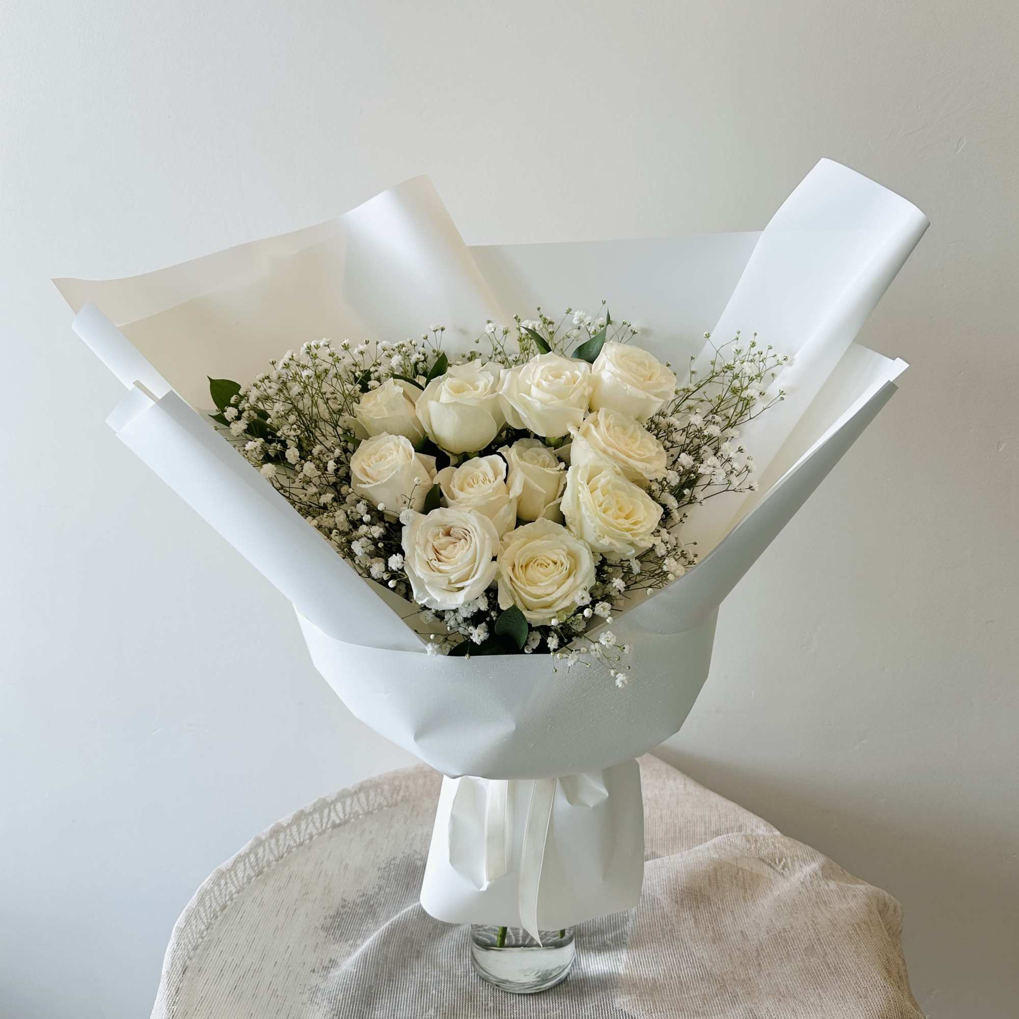 Bouquet of cream roses with baby's breath in white wrapping