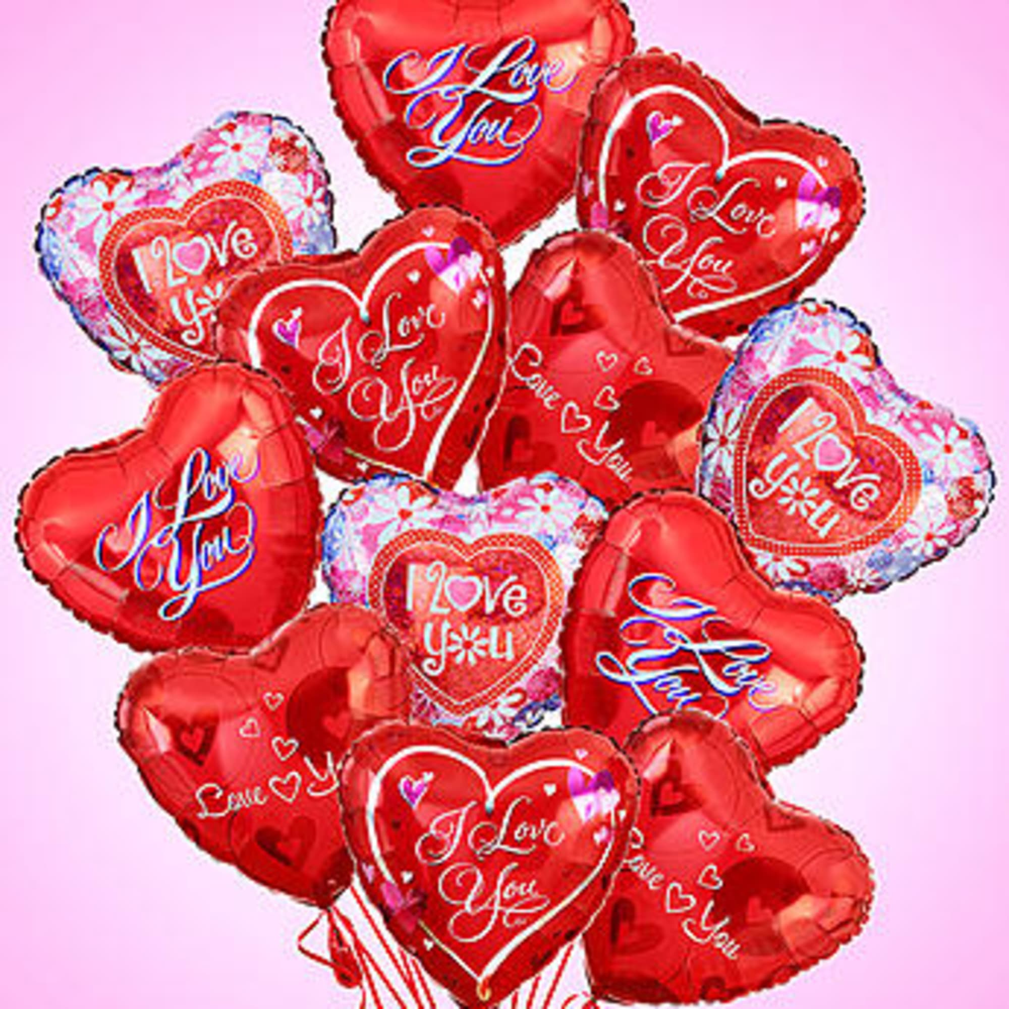Cluster of red heart-shaped balloons with love messages on a pink background