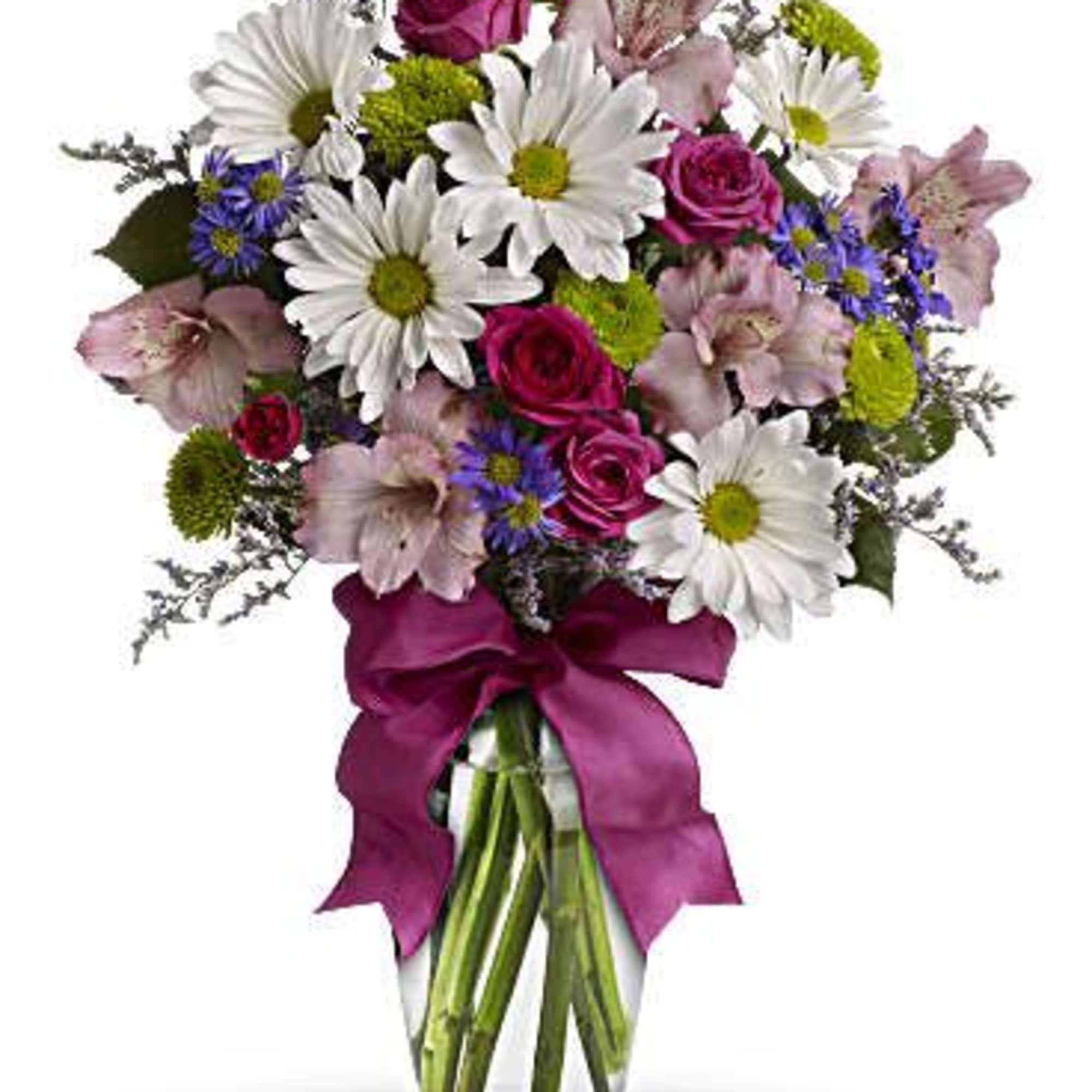 Mixed bouquet of daisies, roses, and alstroemeria in a glass vase with a ribbon