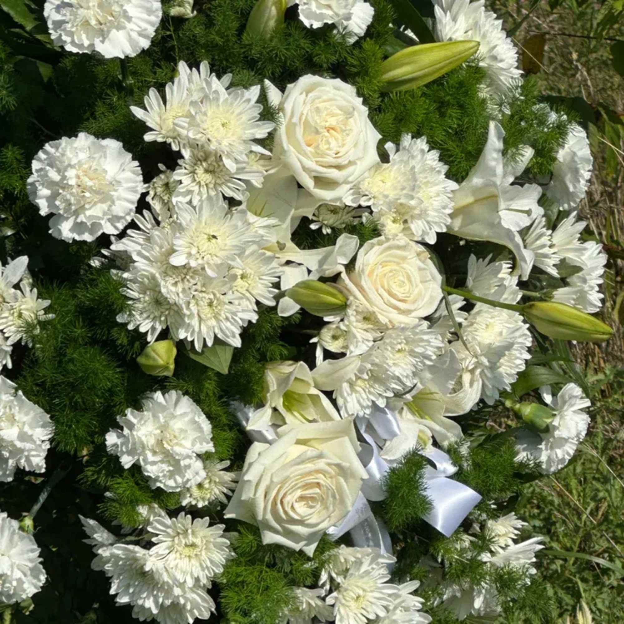 White roses and chrysanthemums arranged with lilies and ribbon