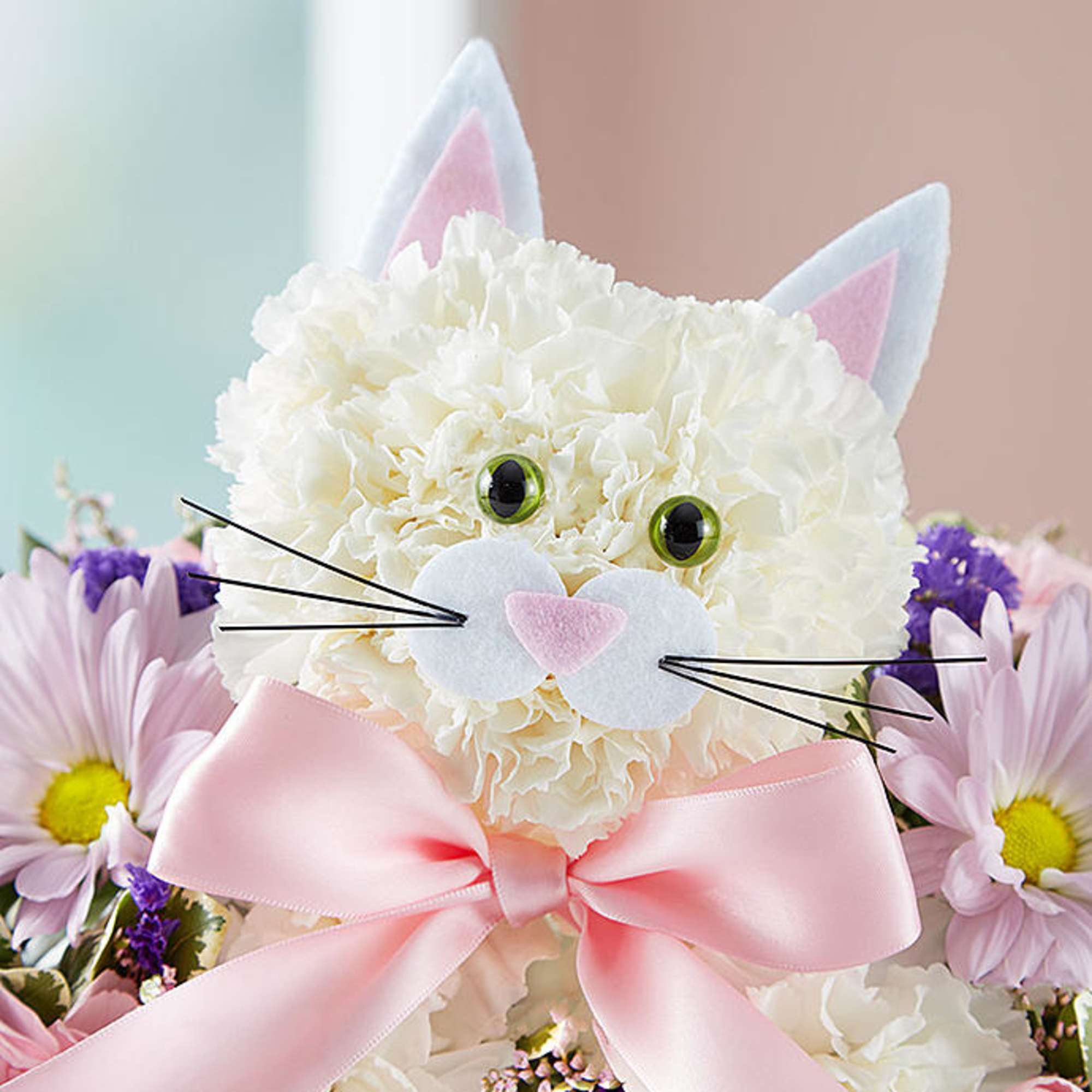 White floral cat face with pink ears and bow, surrounded by daisies