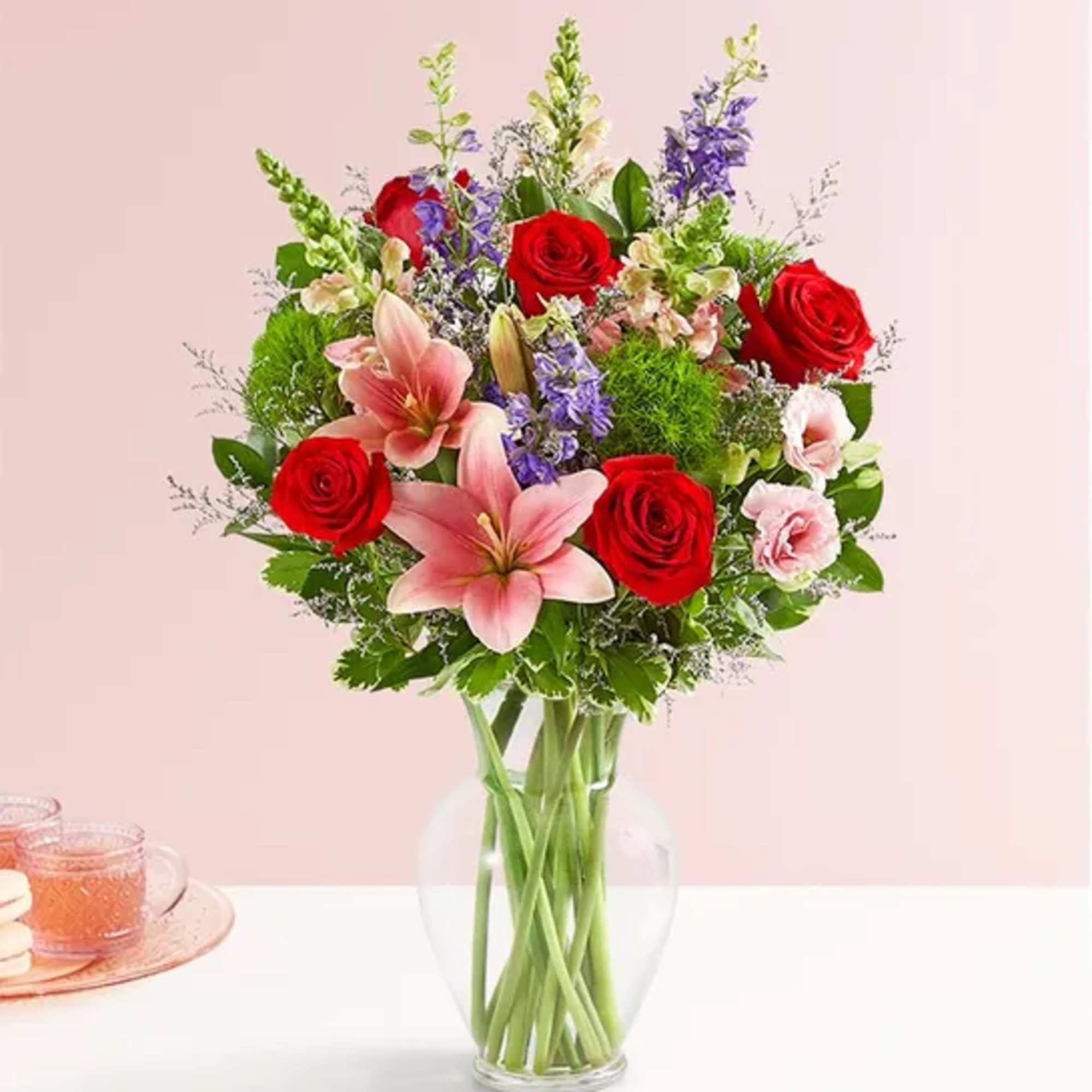 Bouquet of red roses and pink lilies in a clear glass vase