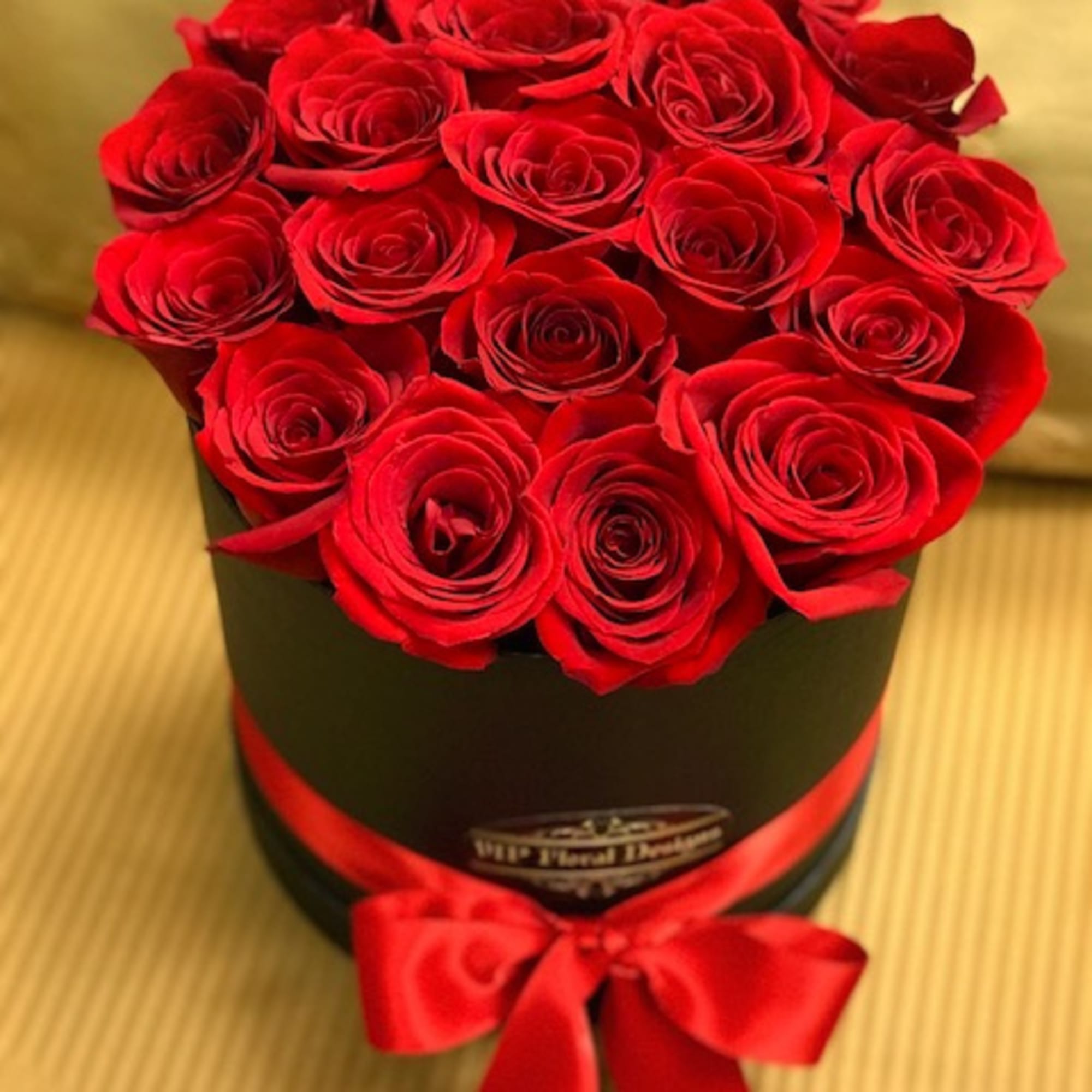 Red roses arranged in a black round box with a red ribbon
