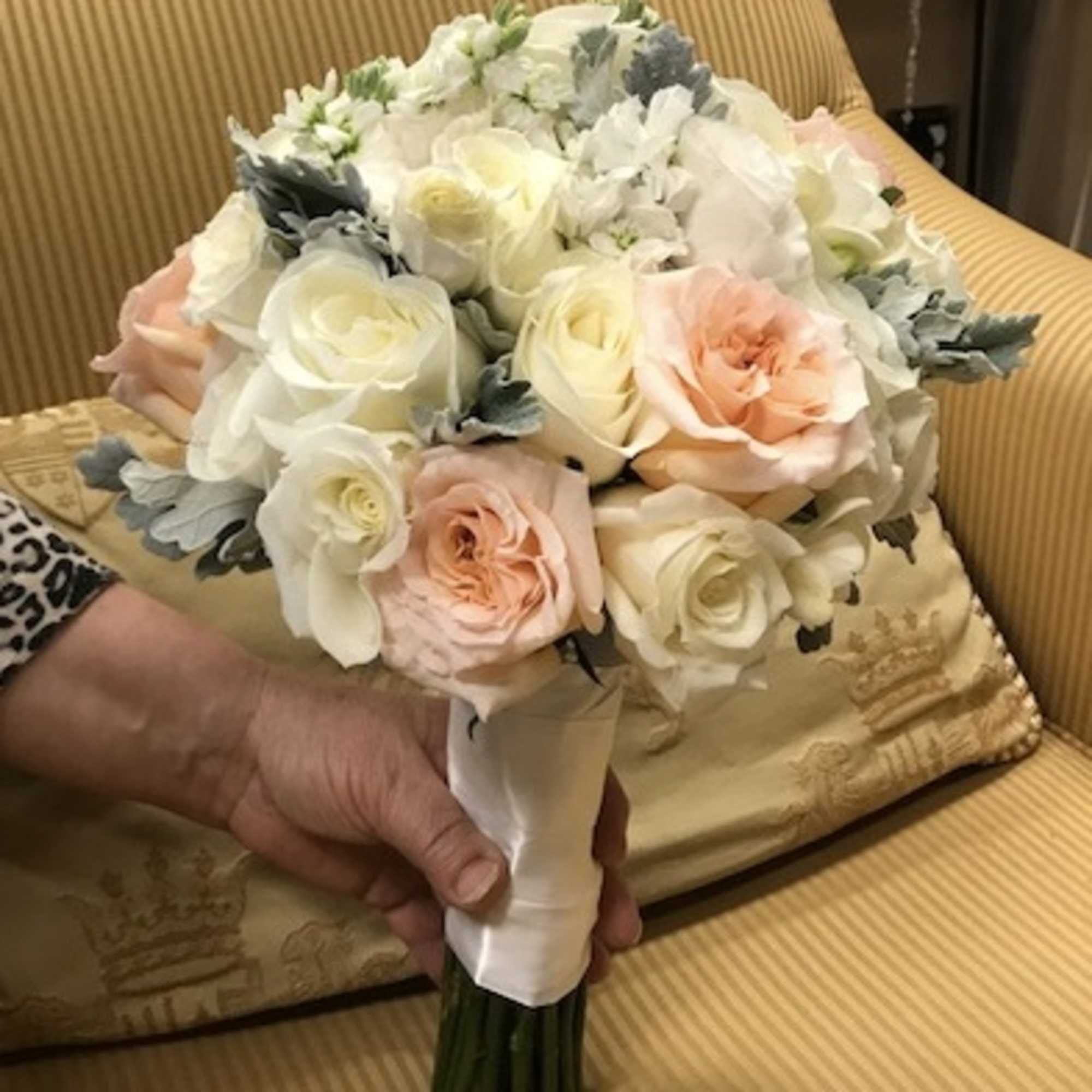 Handheld bouquet of white and blush roses wrapped in white ribbon