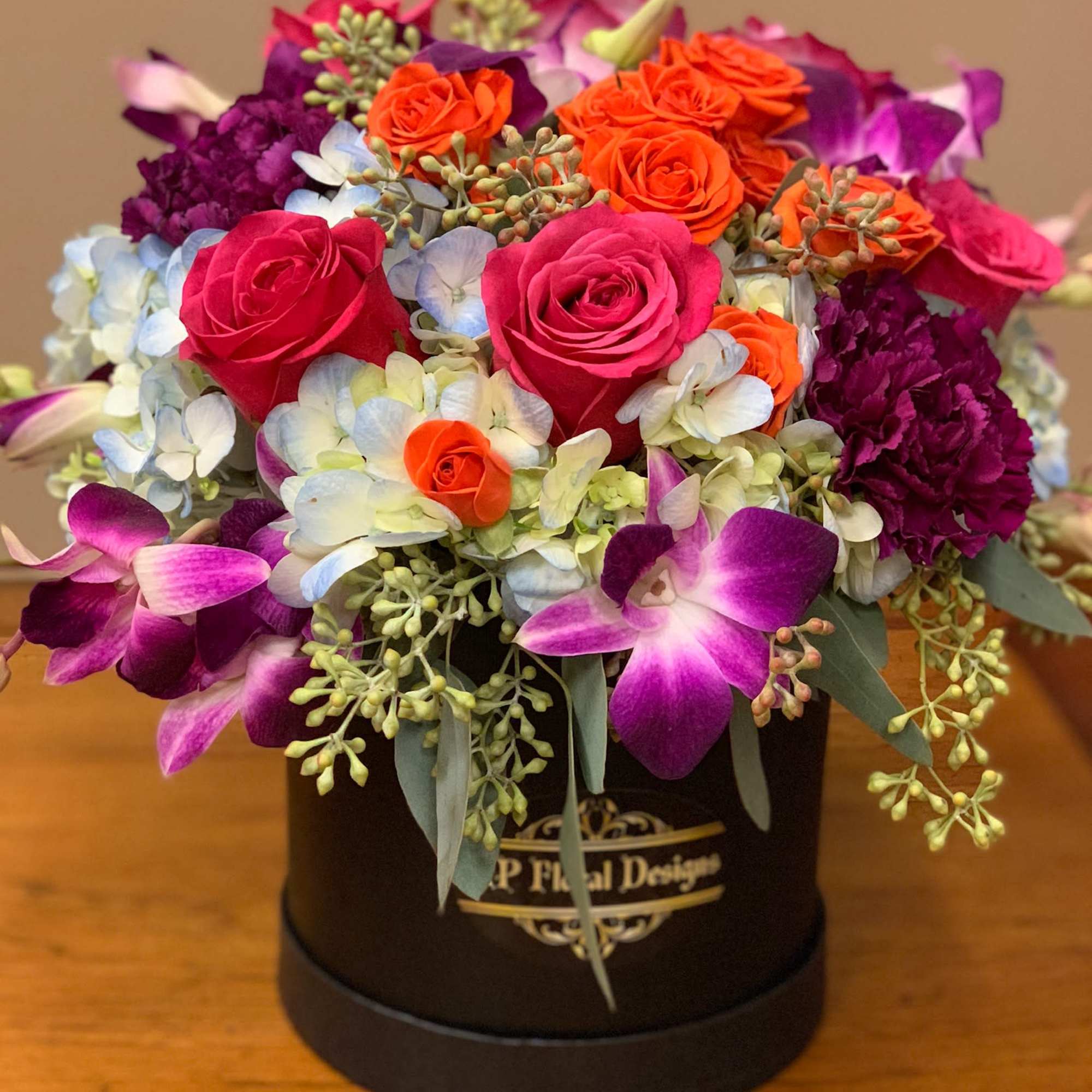 Mixed bouquet of roses and orchids in a black hat box