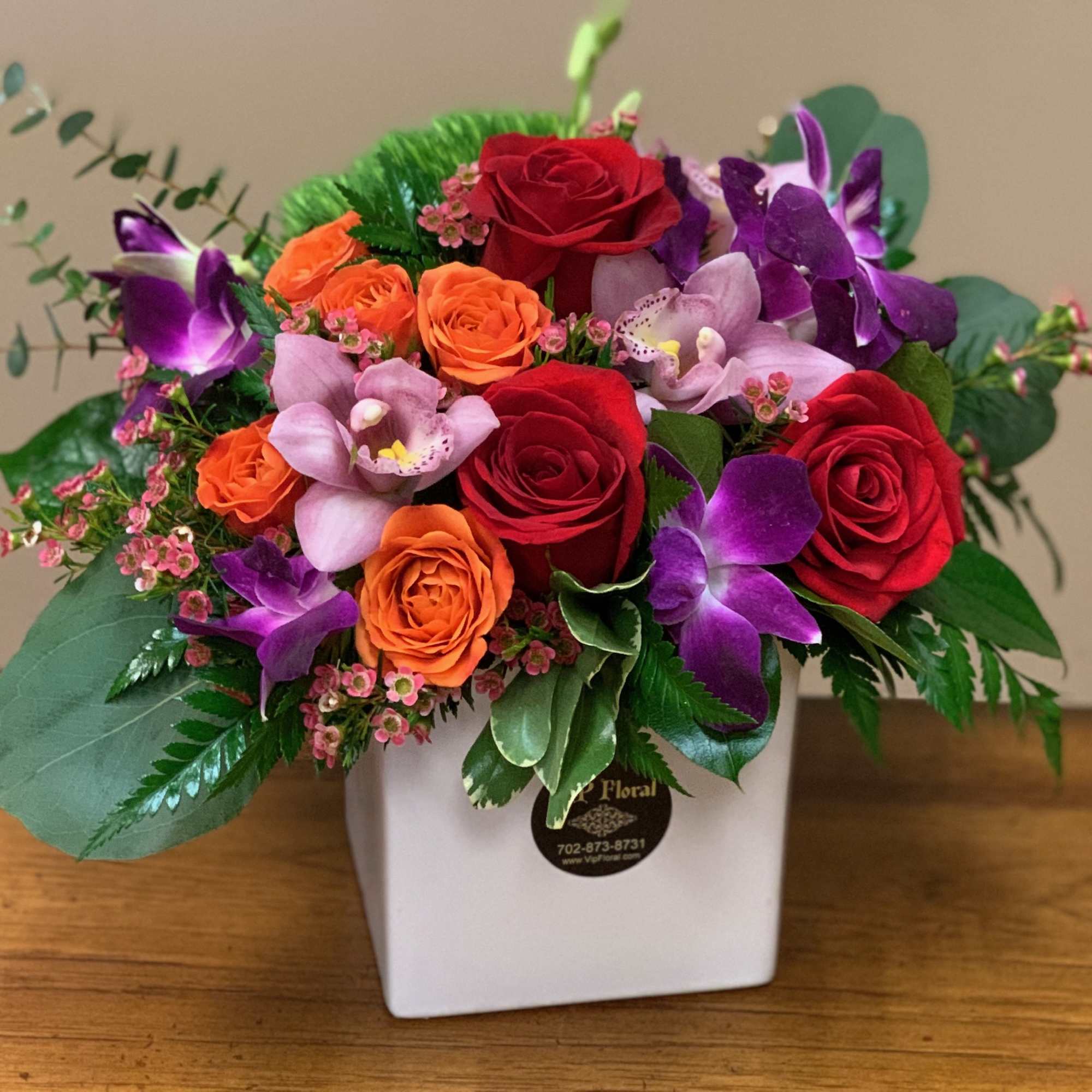Mixed bouquet of red, orange, and purple flowers in a white vase
